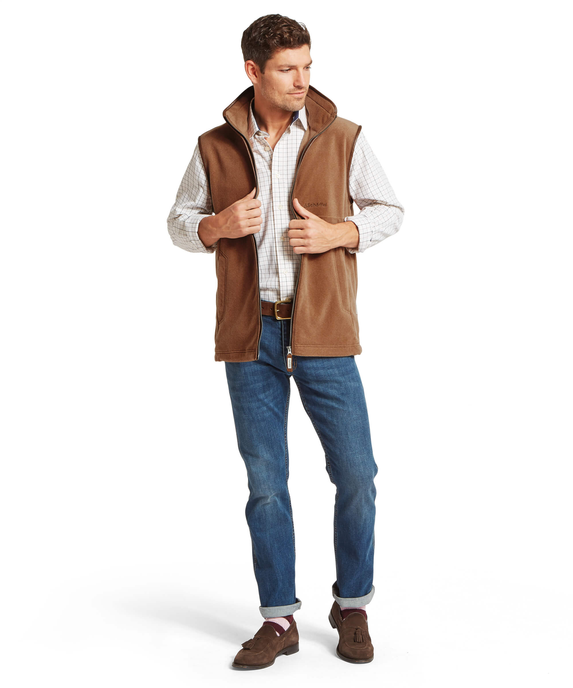 Man wearing a brown fleece gilet over a white shirt, blue jeans, and brown shoes on a white background