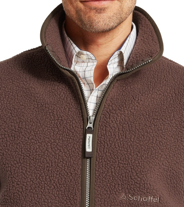 Schöffel Oakham men's retro fleece gilet in brown, close-up of textured sherpa fabric, high collar and full-length zip with branded pull tag, worn over checked shirt