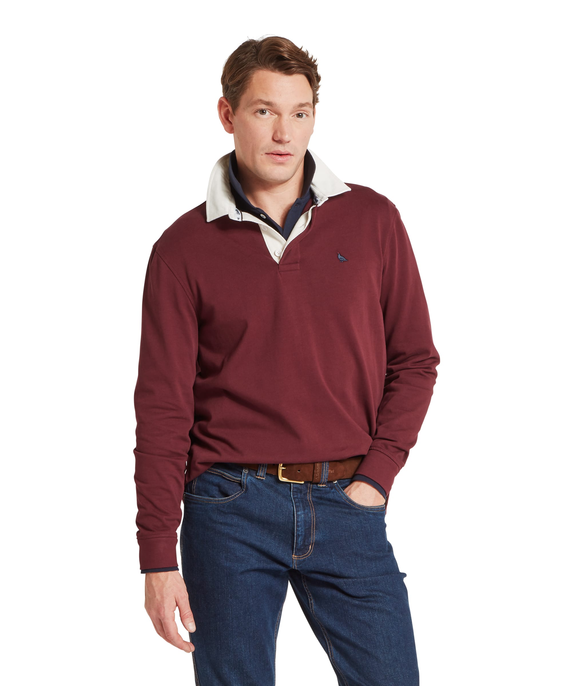 Schöffel Men's Porthallow Rugby Shirt in burgundy red — front view showing contrast cream and navy collar, embroidered pheasant logo and long sleeves, worn with dark blue jeans and a tan leather belt