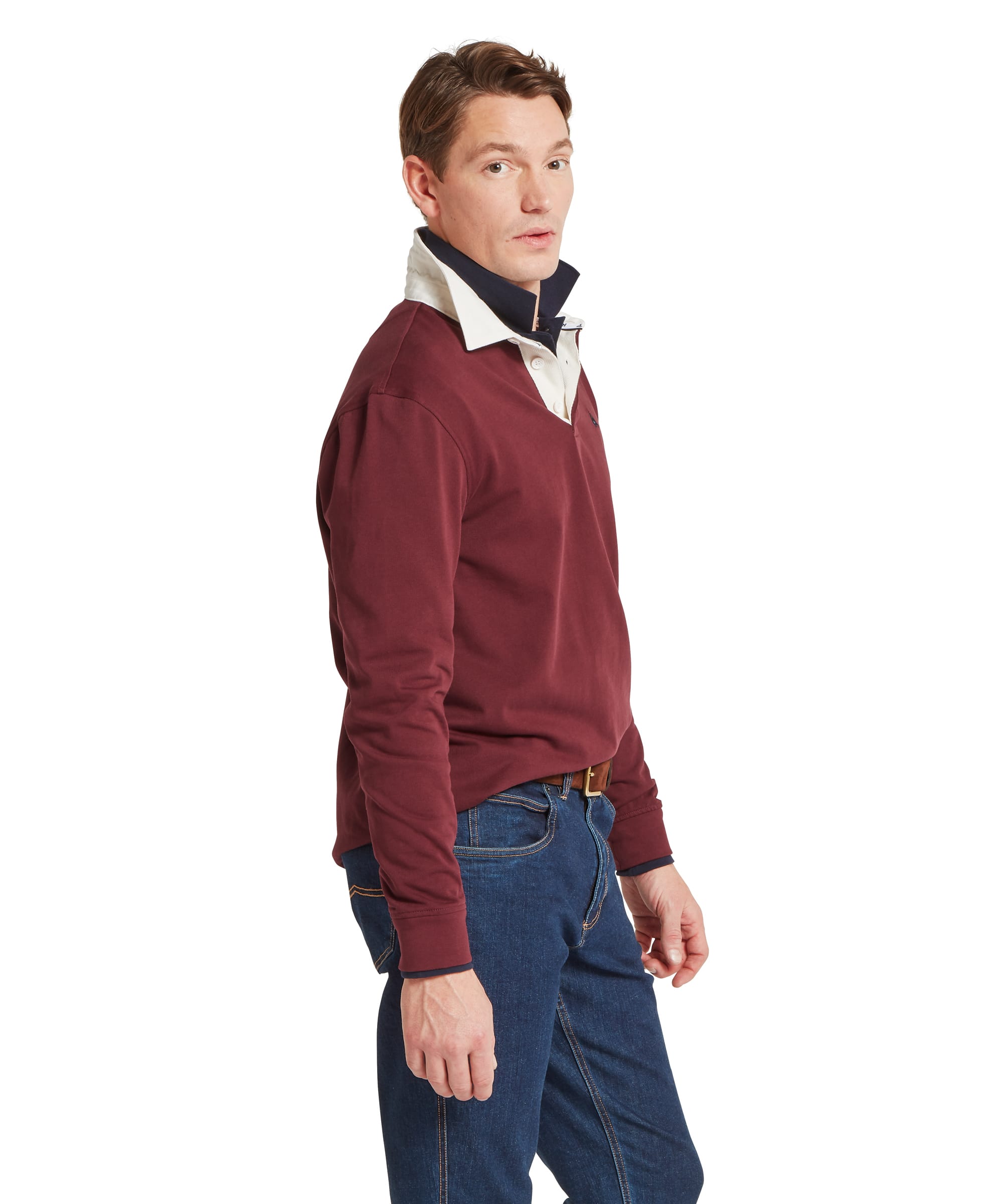 Schöffel Men's Porthallow Rugby Shirt in burgundy red — three-quarter side view showing relaxed fit, ribbed cuffs and overall silhouette, worn with dark denim jeans and a tan belt