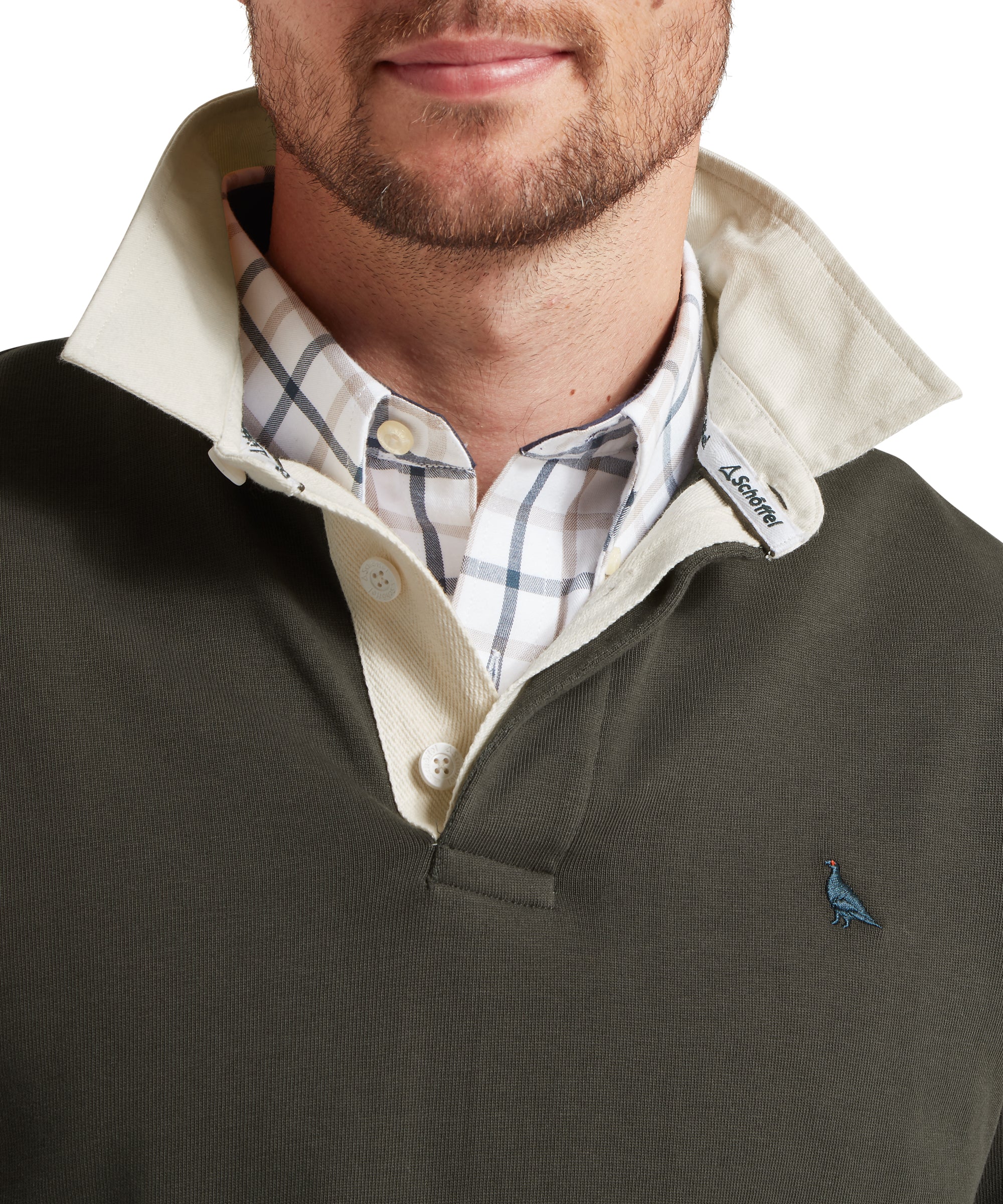 Man wearing a green rugby top with a plaid shirt underneath, featuring a brand logo.