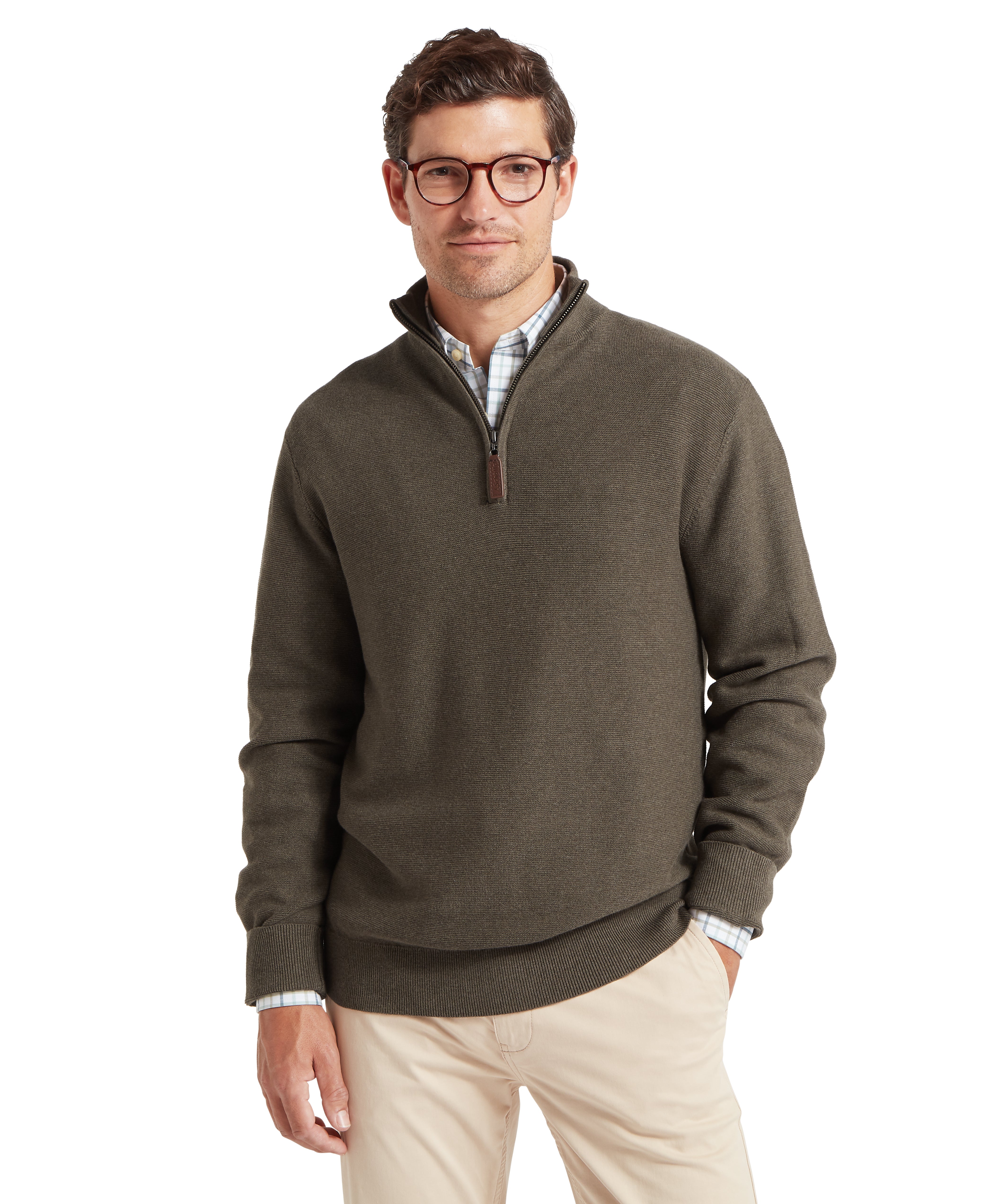 Man wearing a green quarter-zip sweater with one hand in his pocket against a white background