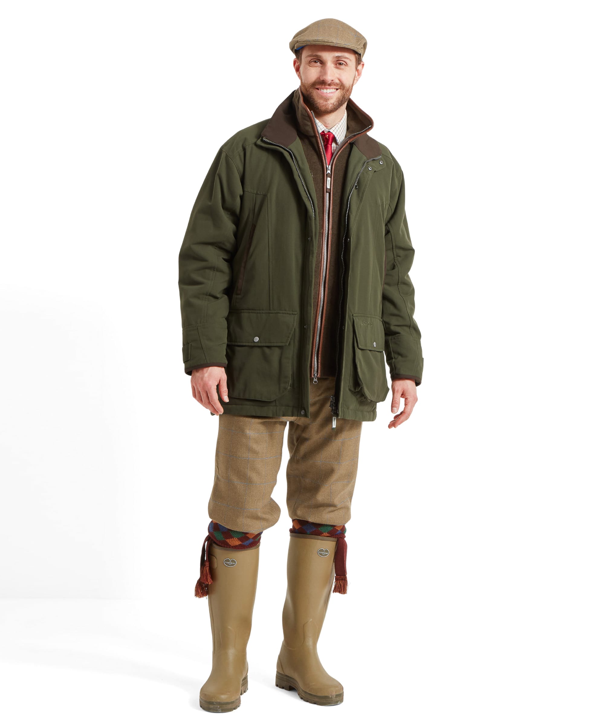 Schöffel Men's Ptarmigan Classic Coat in dark olive green — close-up three-quarter view showing brown leather-trim collar, dual zip fastening, shoulder shooting patch and Schöffel branding, styled with a tweed flat cap