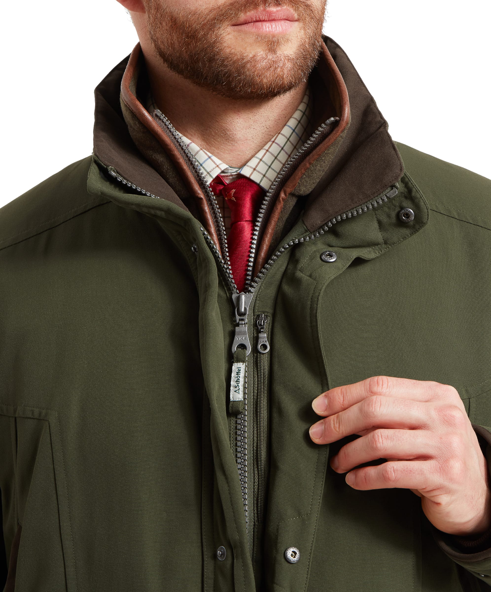 Schöffel Men's Ptarmigan Classic Coat in dark olive green — close-up of the dual front zip fastening with Schöffel branded zip pull, leather-trim collar and press-stud storm guard, layered over a checked shirt and red tie