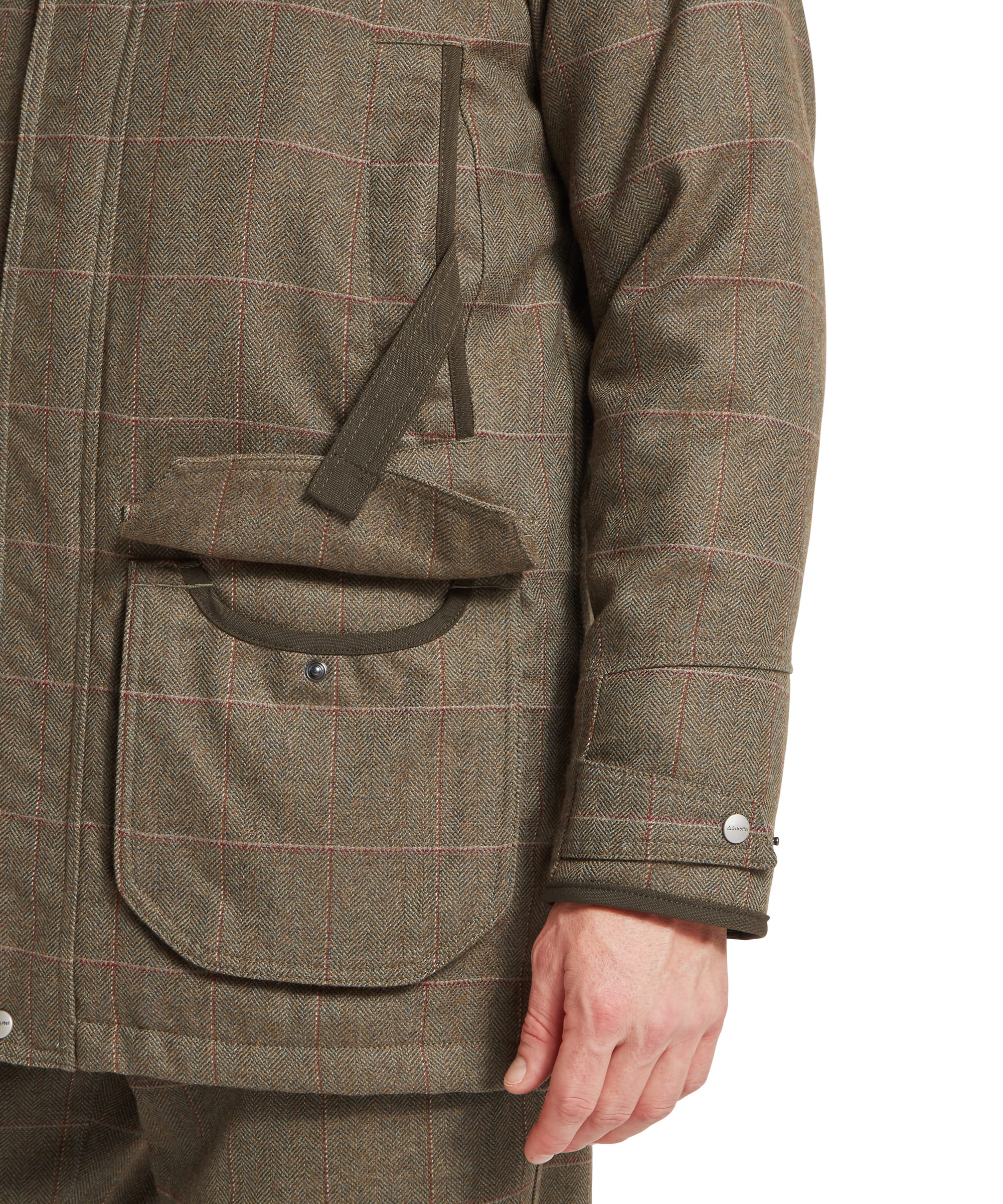 Schöffel Men's Ptarmigan Tweed Classic Coat in Lovat brown windowpane check — close-up of the lower front body showing twin bellows pockets with press-stud flaps, Schöffel embroidered chest logo, press-stud storm hem guard and olive-bound cuffs with press-stud adjusters
