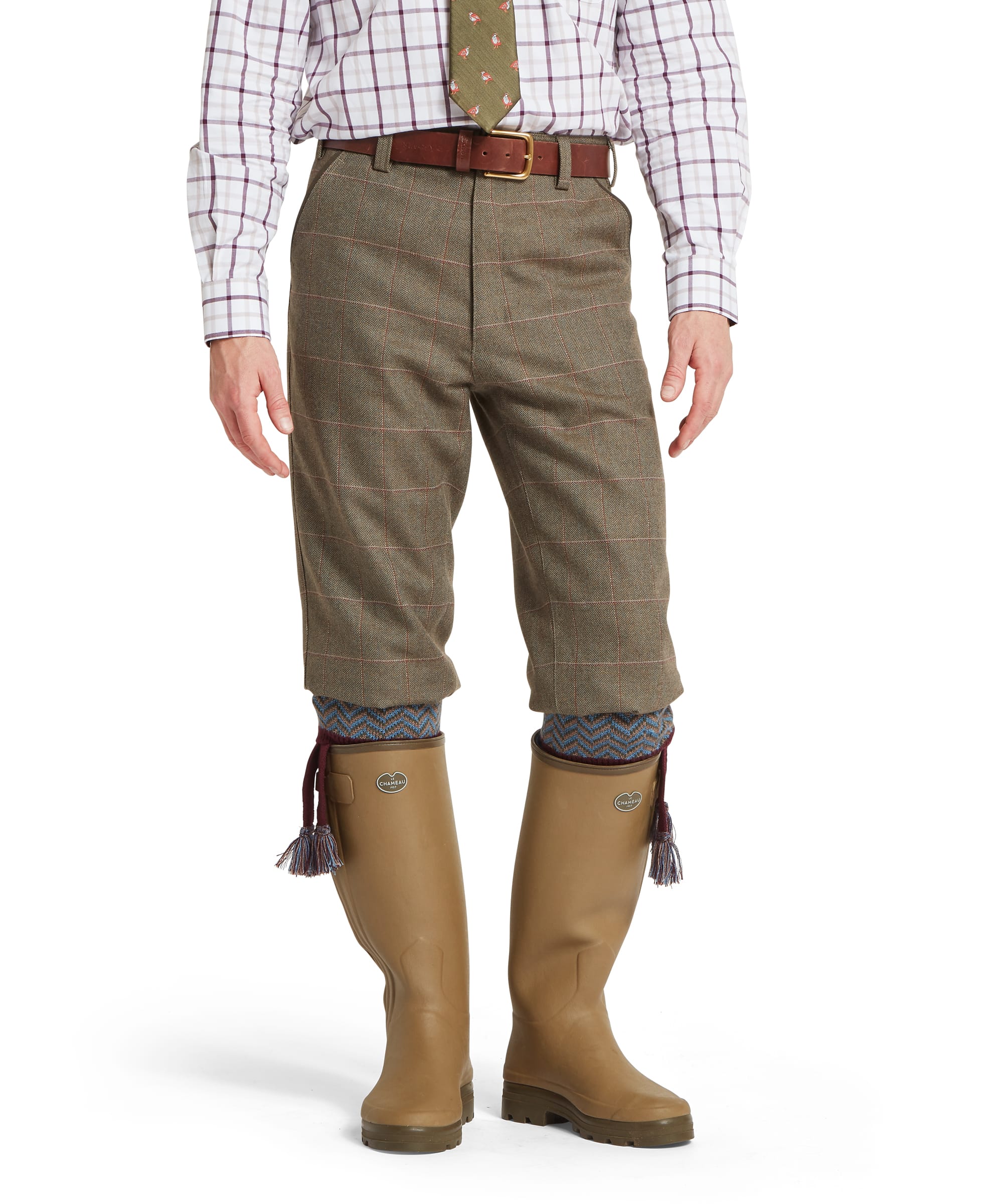 Schöffel Men's Ptarmigan Tweed Plus Twos in Lovat brown Lochlane windowpane check — full-length front view showing the traditional plus-two cut in classic British tweed, worn with a checked shirt, pheasant-motif tie, Schöffel leather belt and Le Chameau wellington boots with patterned sock garters