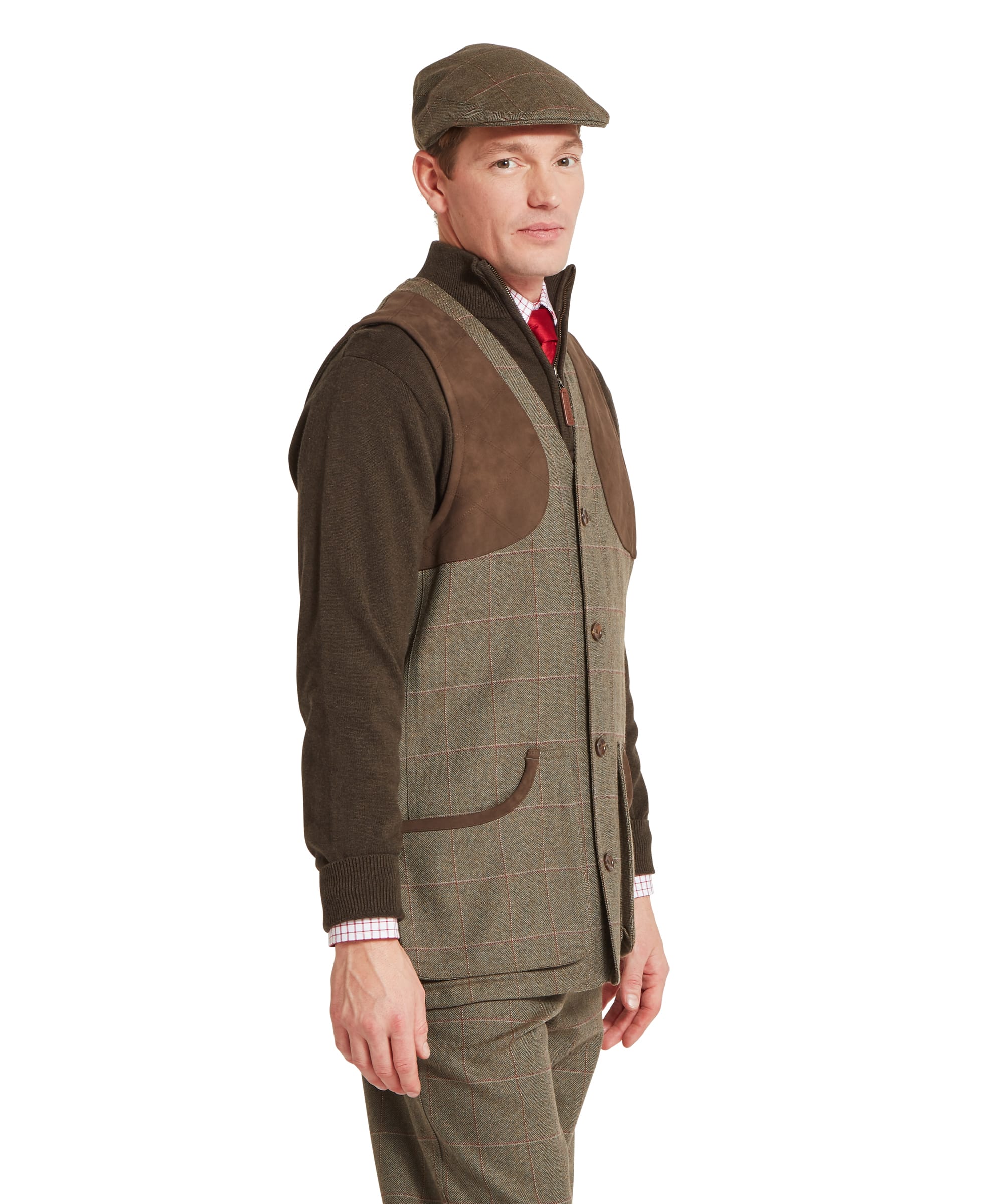 Schöffel Men's Ptarmigan Tweed Waistcoat II in Lovat brown windowpane check — three-quarter side view showing large suede shooting patch, four-button front fastening, lower patch pocket with brown leather trim and Schöffel branding, worn over a zip-neck merino gilet with tweed plus twos and flat cap