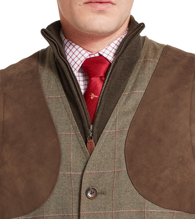 Schöffel Ptarmigan tweed waistcoat II in brown, close-up of herringbone check fabric with contrast suede shoulder patches and quilted panels, zip and button fastening, styled with shirt and tie