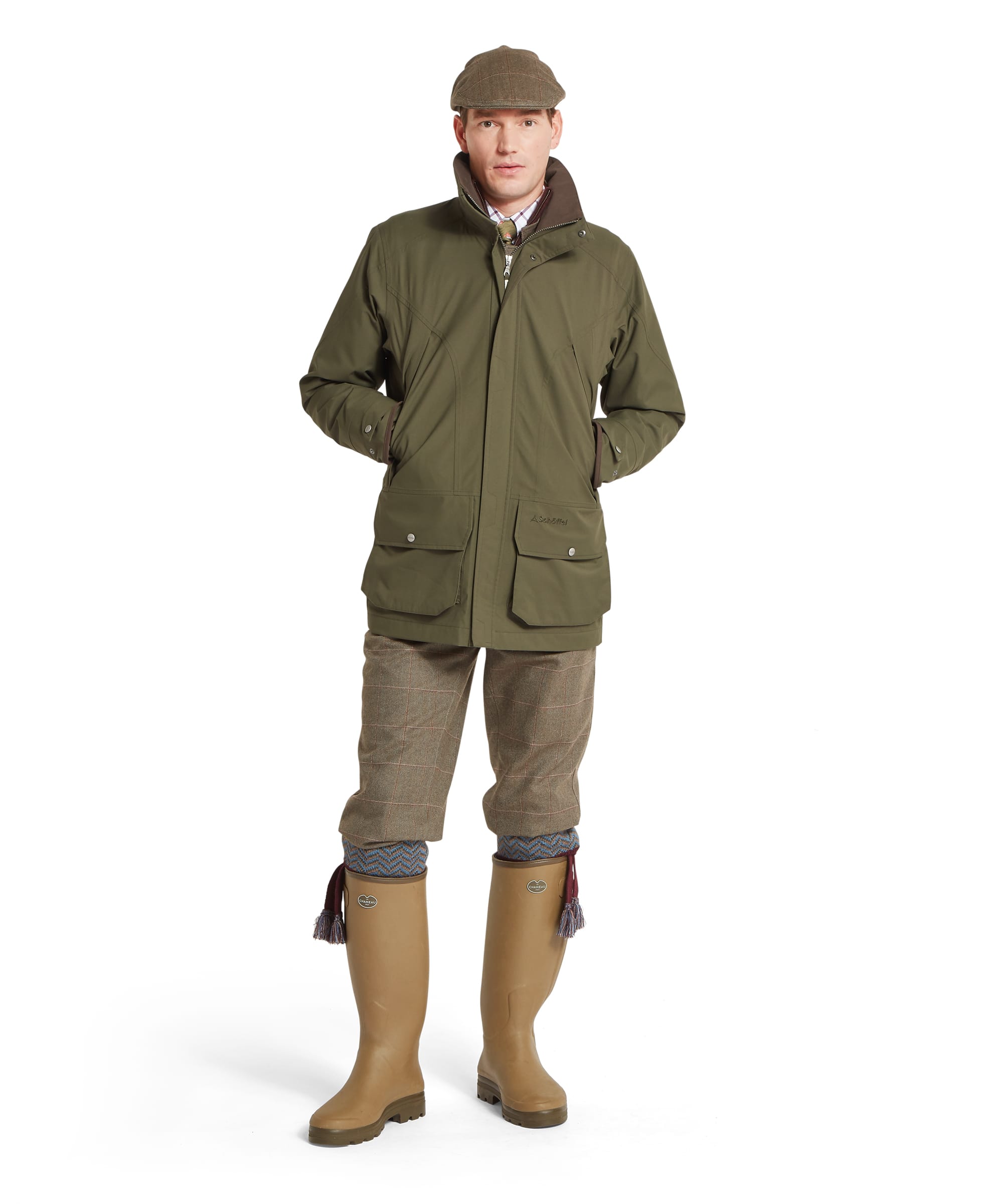 Schöffel Men's Snipe Ultralight Coat in dark olive green — full-length front view showing the coat closed with zip and press-stud placket, large bellows pockets with Schöffel branding, articulated sleeves and brown-bound cuffs with press-stud adjusters, worn with tweed plus twos and Le Chameau wellington boots