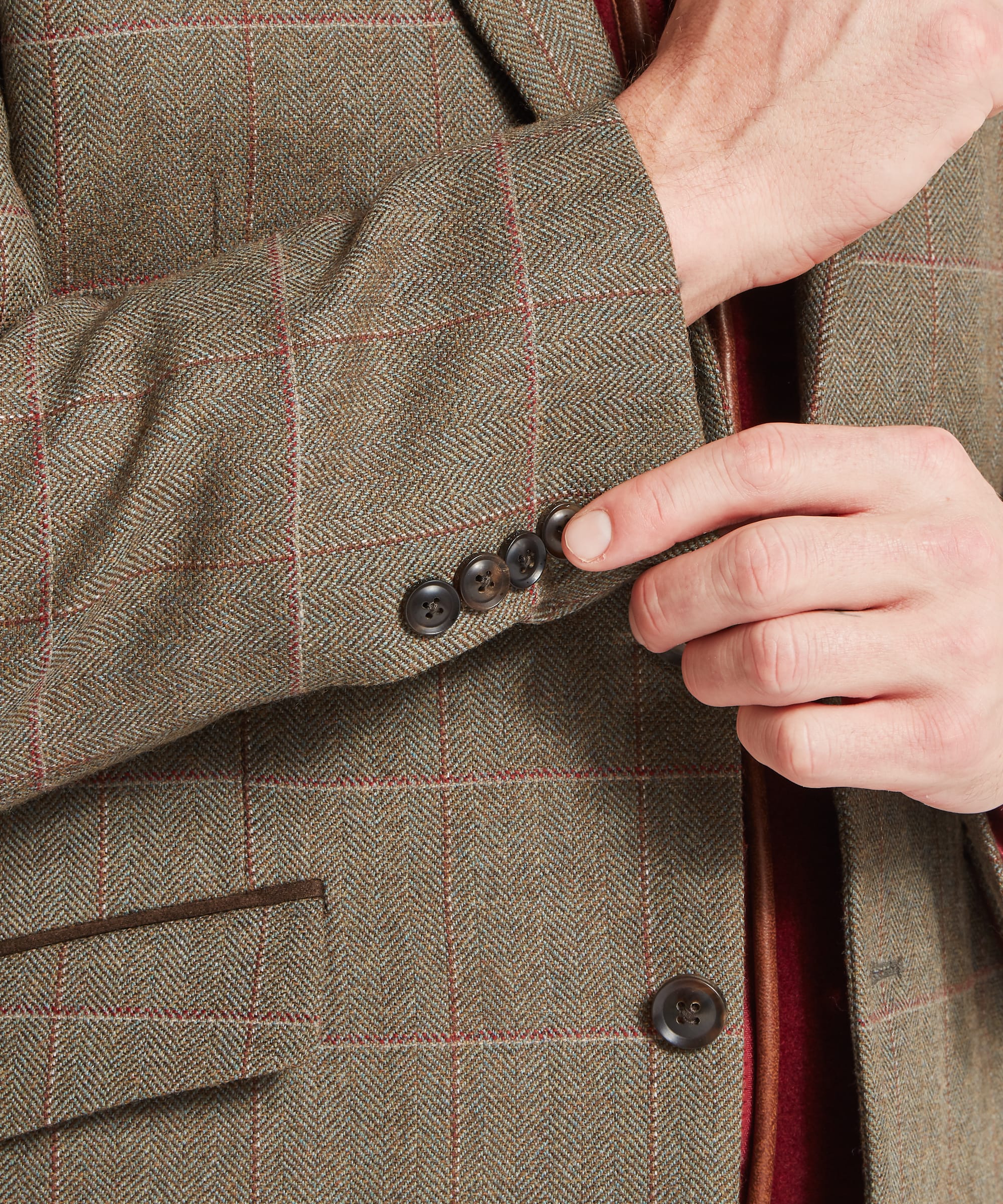 Schöffel Men's St Andrews Tweed Sports Jacket in Lovat brown Lochlane windowpane check — three-quarter front view showing notched lapel, two-button fastening, flap lower pockets and suede-bound jetted chest pocket, layered over a burgundy zip-neck gilet with checked shirt, worn with brown corduroy trousers