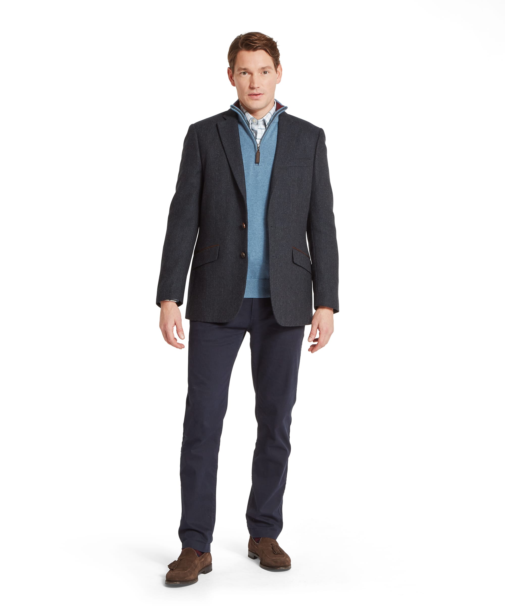 Schöffel Men's St Andrews Tweed Sports Jacket in navy herringbone — front view showing classic two-button construction, notched lapels, flap pockets with brown suede trim detail, layered over a light blue zip-neck gilet with Schöffel leather zip pull, checked shirt and navy trousers