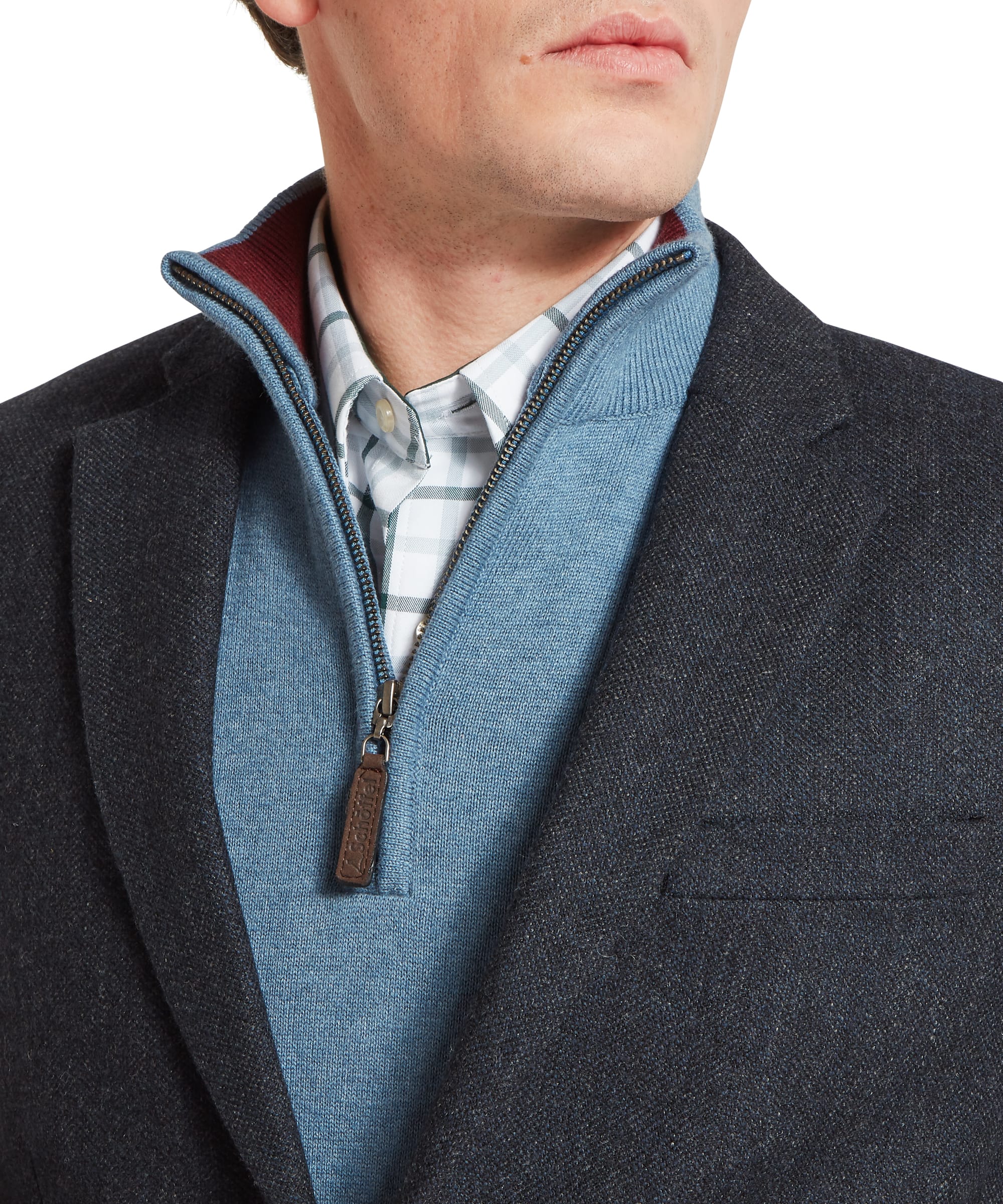Schöffel Men's St Andrews Tweed Sports Jacket in navy herringbone — three-quarter side view showing notched lapel, flap pockets, two-button fastening and tailored fit, layered over a light blue zip-neck gilet, worn with navy trousers
