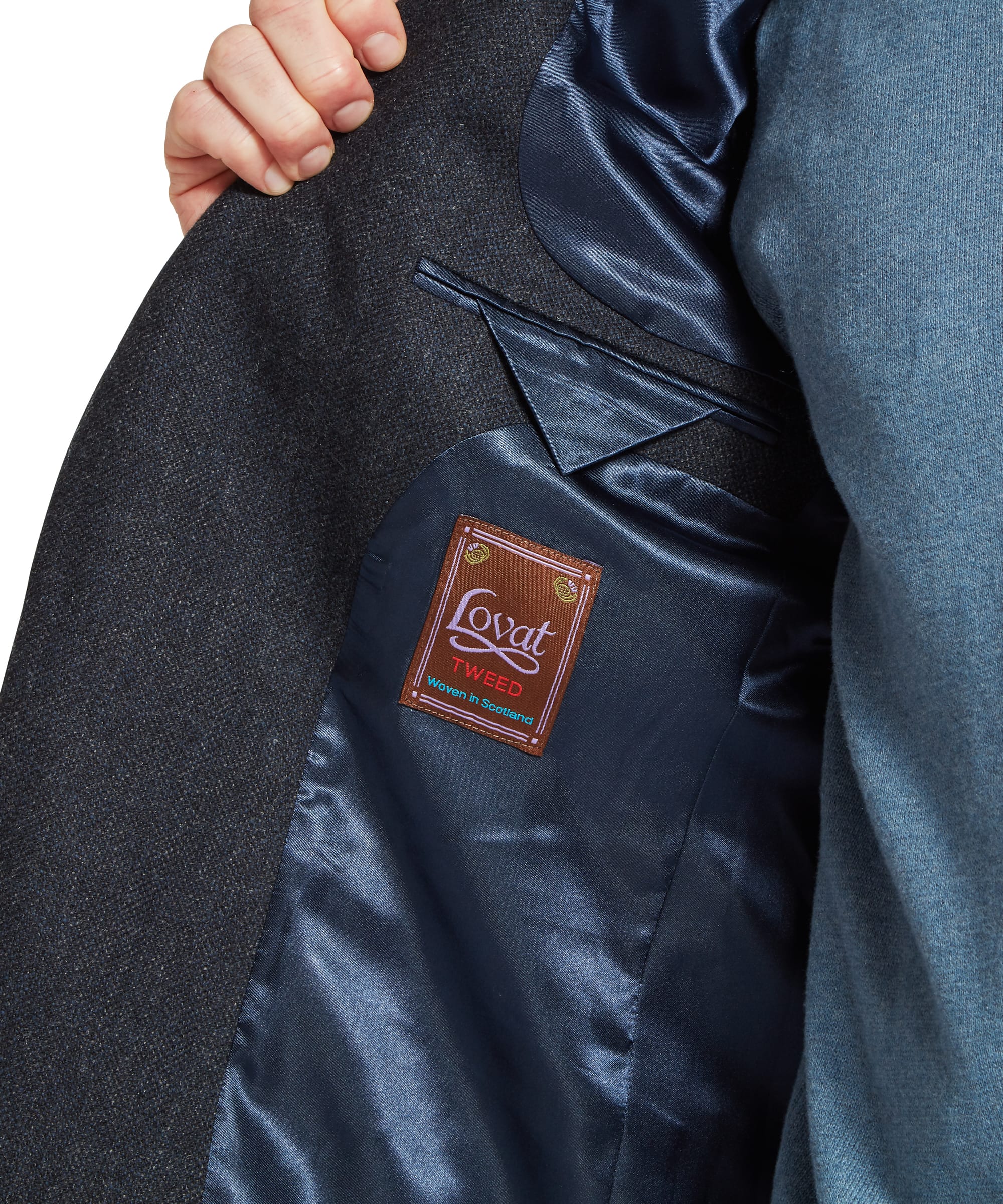 Schöffel Men's St Andrews Tweed Sports Jacket in navy herringbone — interior detail showing the navy satin lining, internal welt pocket and Lovat Tweed "Woven in Scotland" heritage label, coat held open by hand