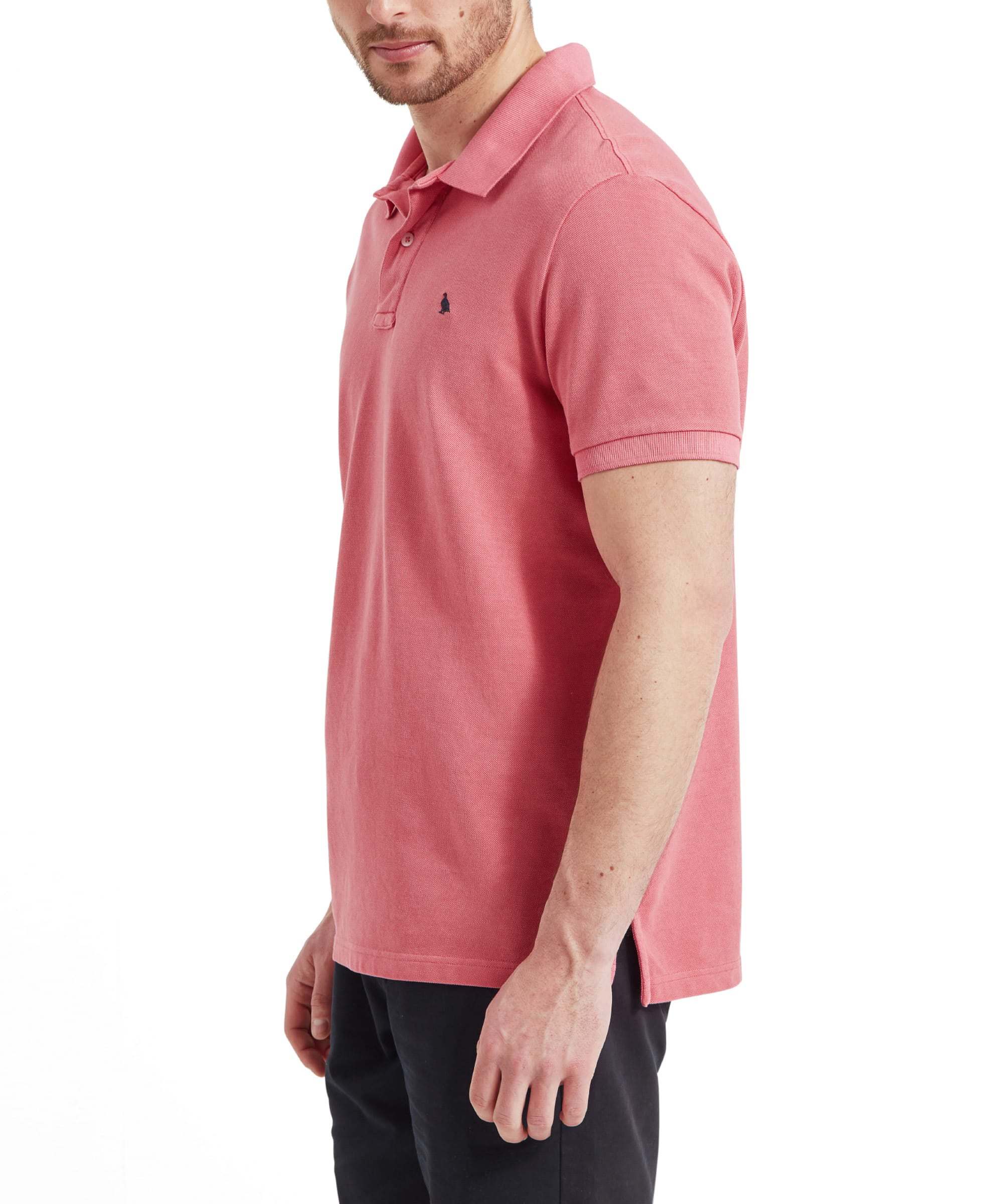 Schöffel Men's St Ives Garment Dyed Polo Shirt in coral pink, side profile on model styled with navy trousers