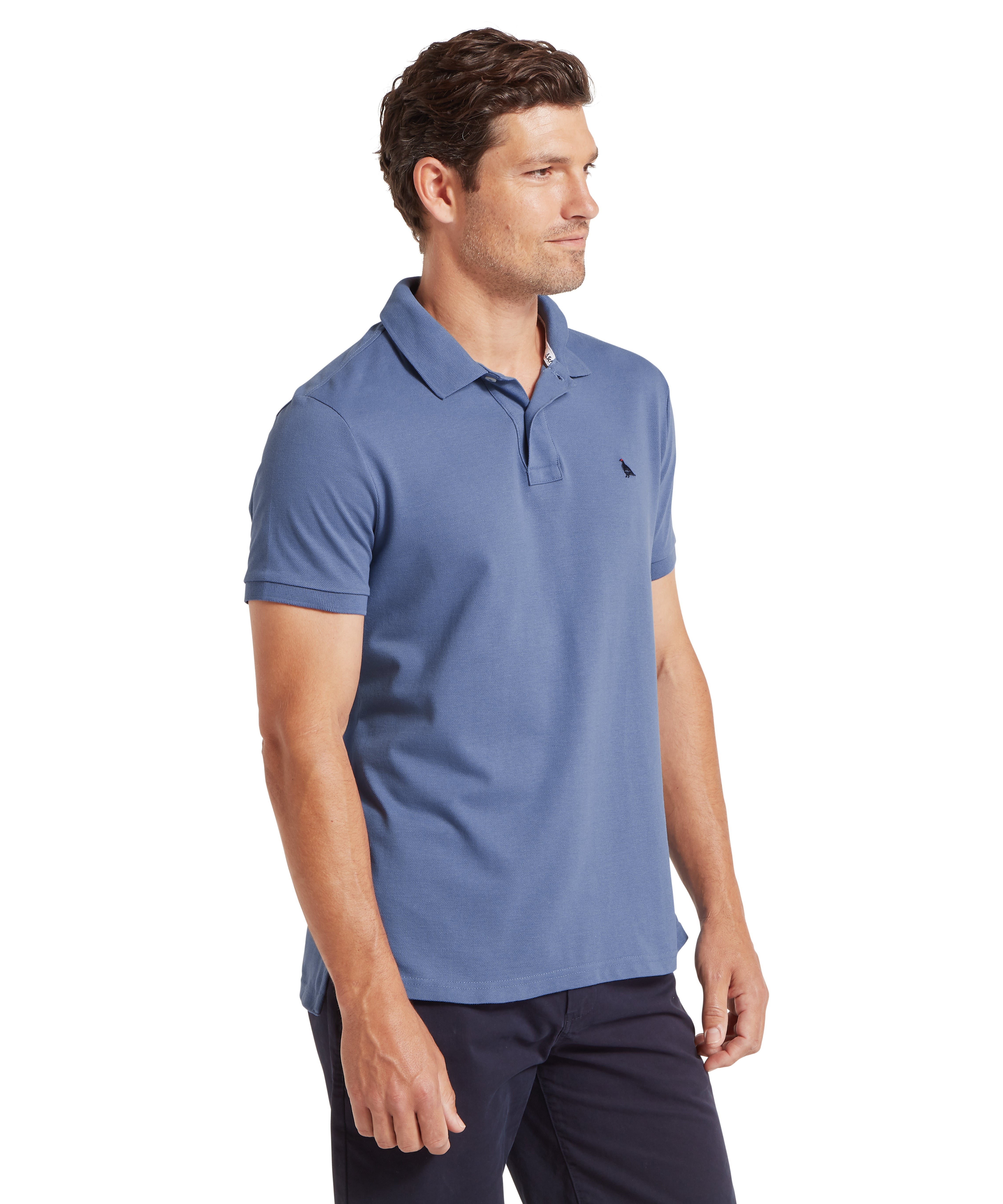 Man standing sideways wearing a blue polo shirt against a white background
