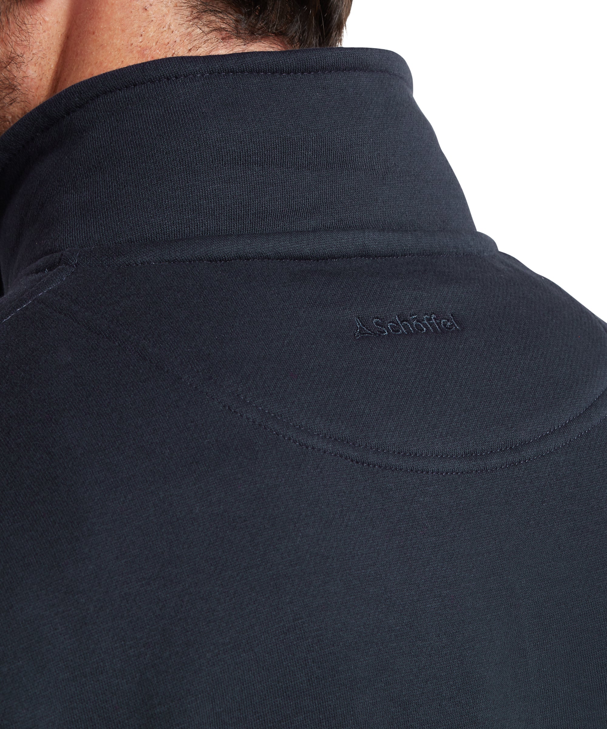 Close-up of a navy blue jacket with a brand logo on the chest area.