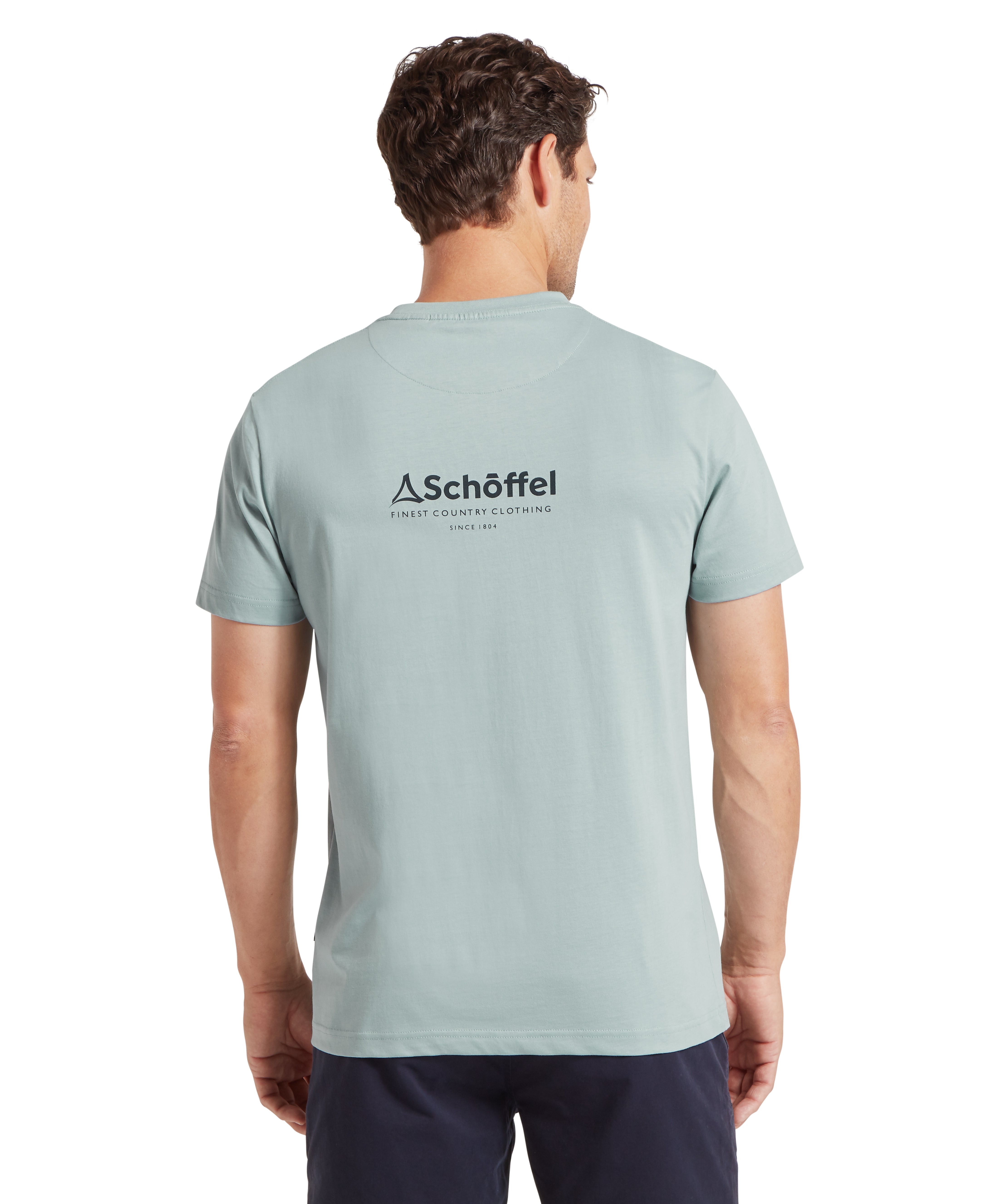 Man wearing a light blue t-shirt with Schöffel logo on the back, standing against a white background