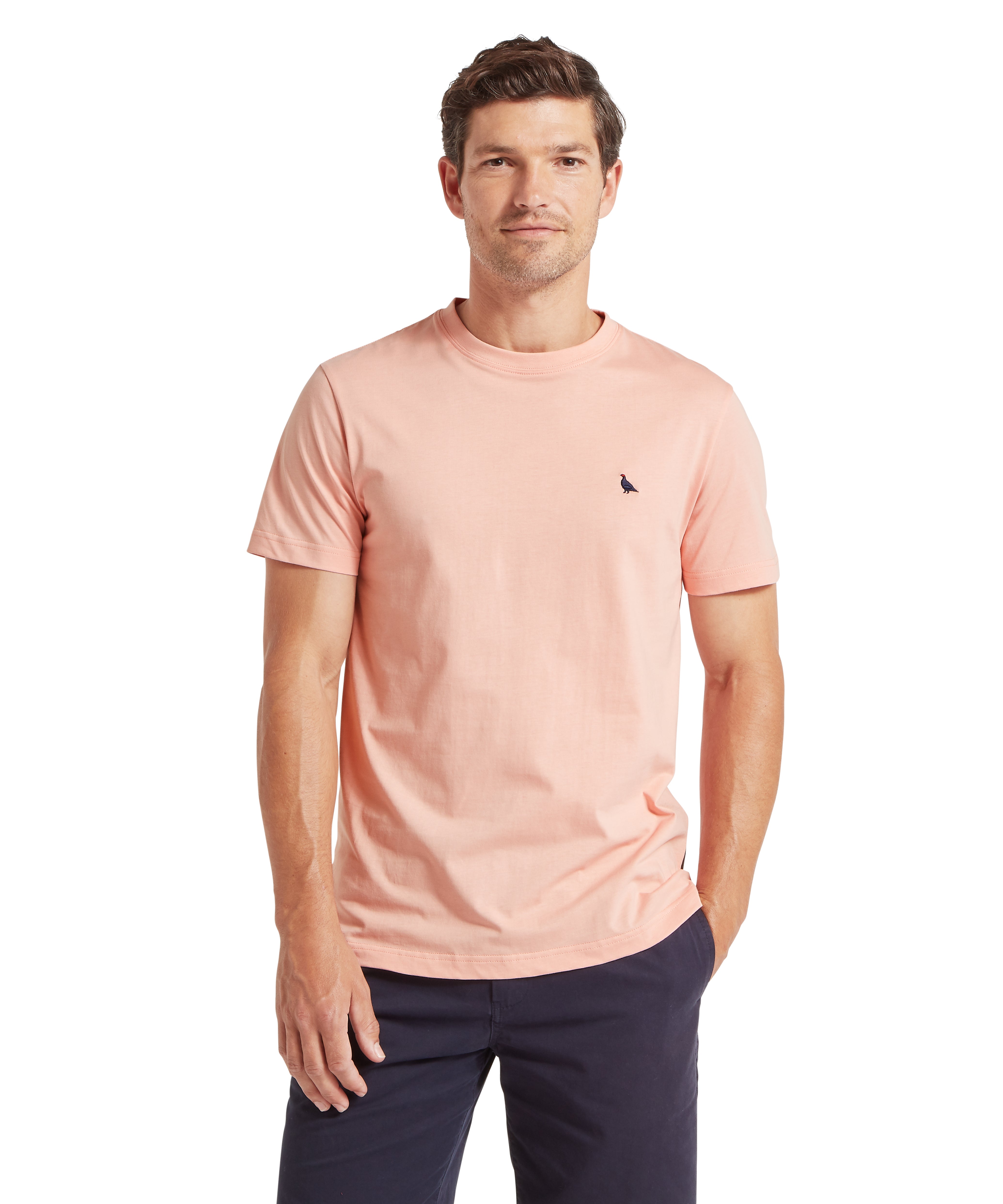 Man wearing a light pink t-shirt with a small ptarmigan logo against a white background