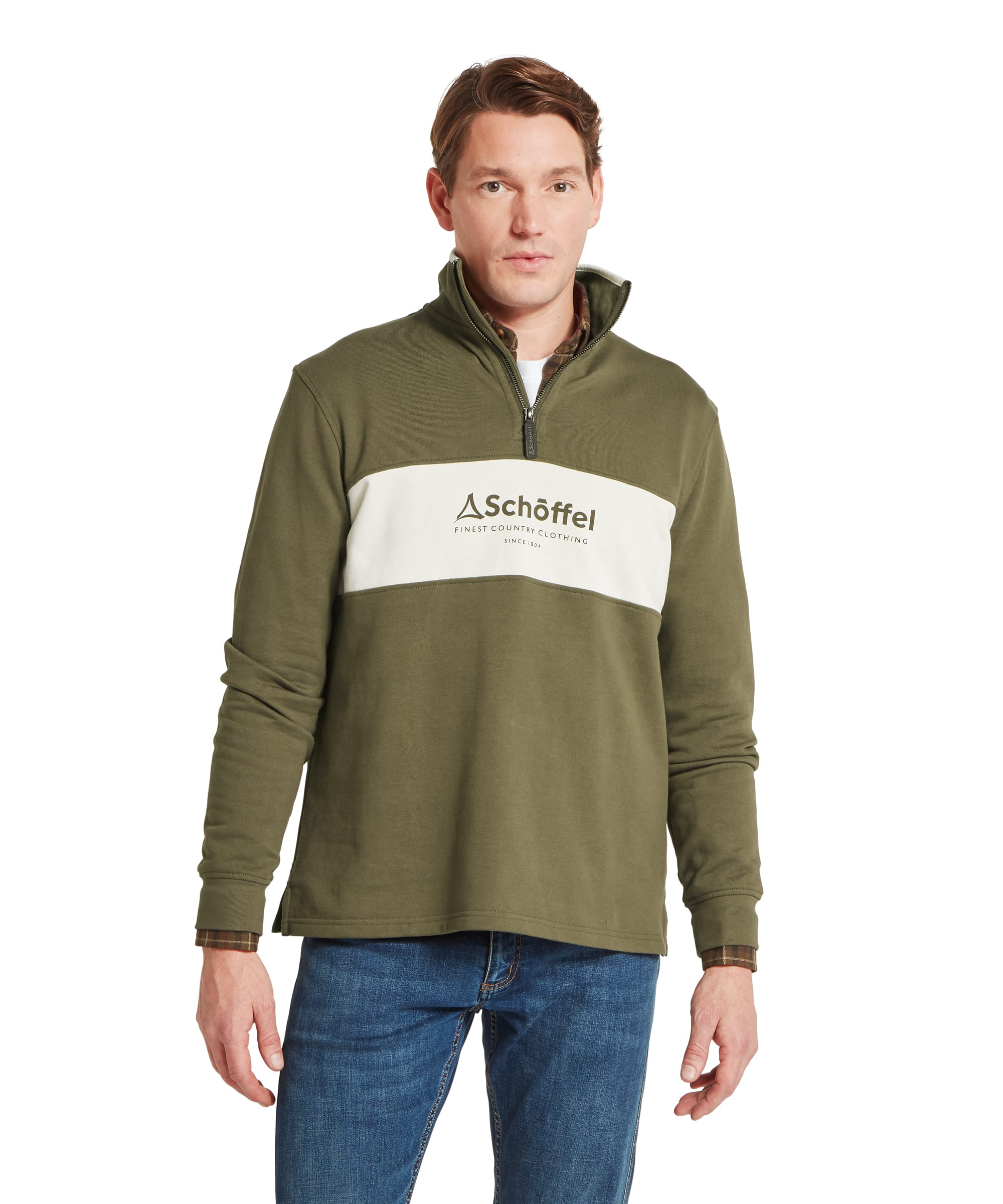 Schöffel Men's Trencrom ¼ Zip in olive green — front view showing the colour-block design with olive upper body and ecru chest panel carrying the Schöffel "Finest Country Clothing Since 1804" heritage logo, quarter-zip stand collar with Schöffel branded leather zip pull, worn over a checked shirt with blue jeans