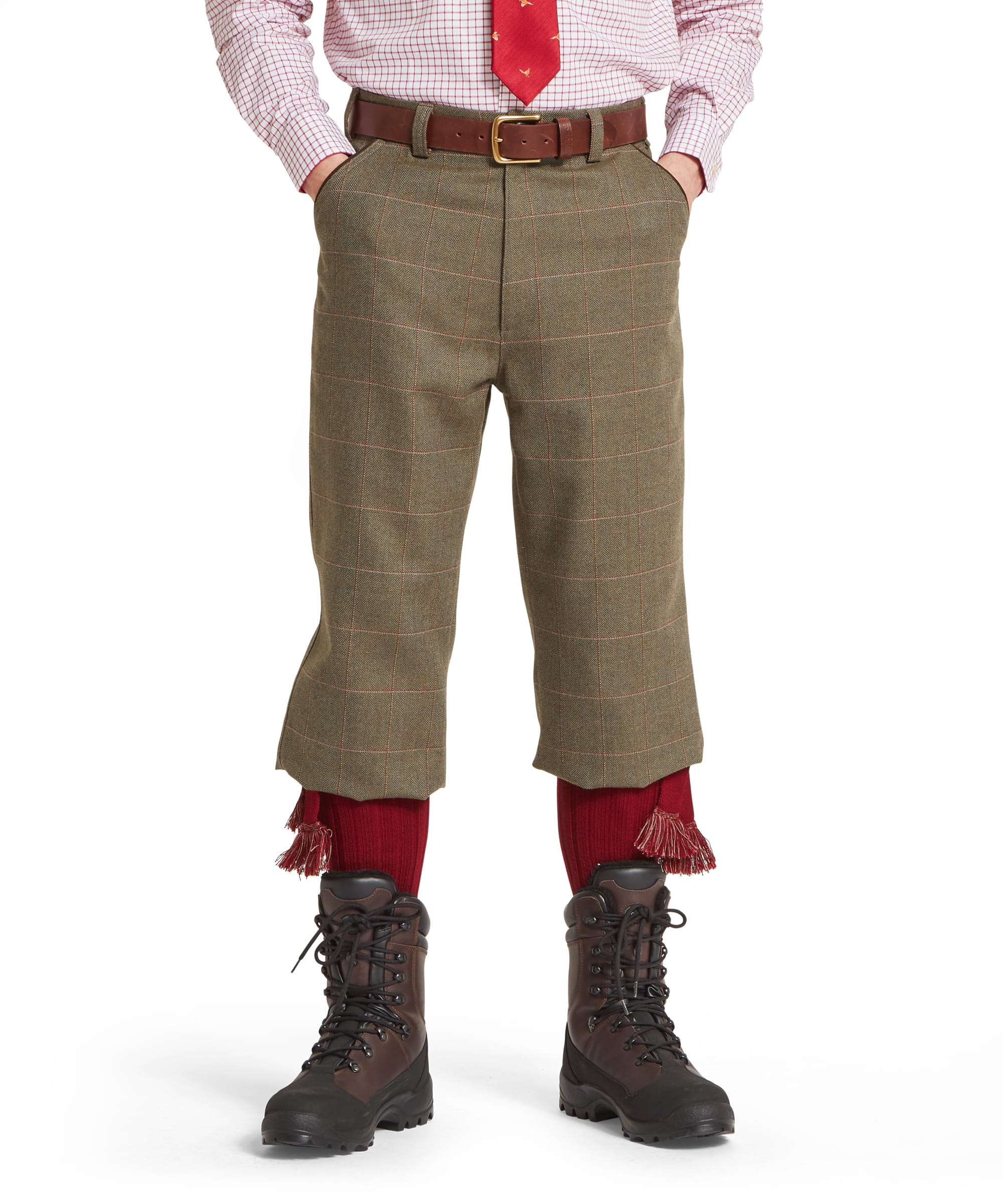 Schöffel Men's Tweed Plus Fours in Lovat brown Lochlane windowpane check — front view showing the traditional wide-cut plus-four silhouette in classic herringbone tweed with red and buff overcheck, worn with a checked shirt, pheasant-motif tie, Schöffel leather belt, red sock garters and country walking boots