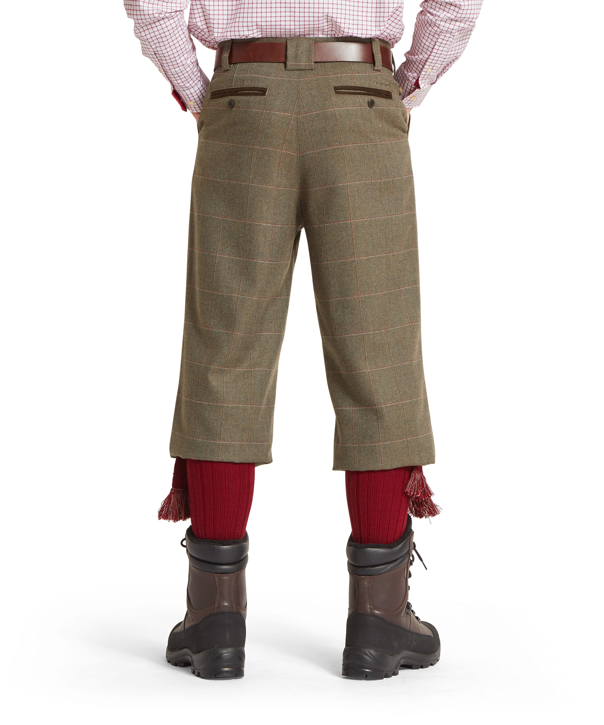 Person wearing green tweed plus fours, red socks, and brown boots on a white background
