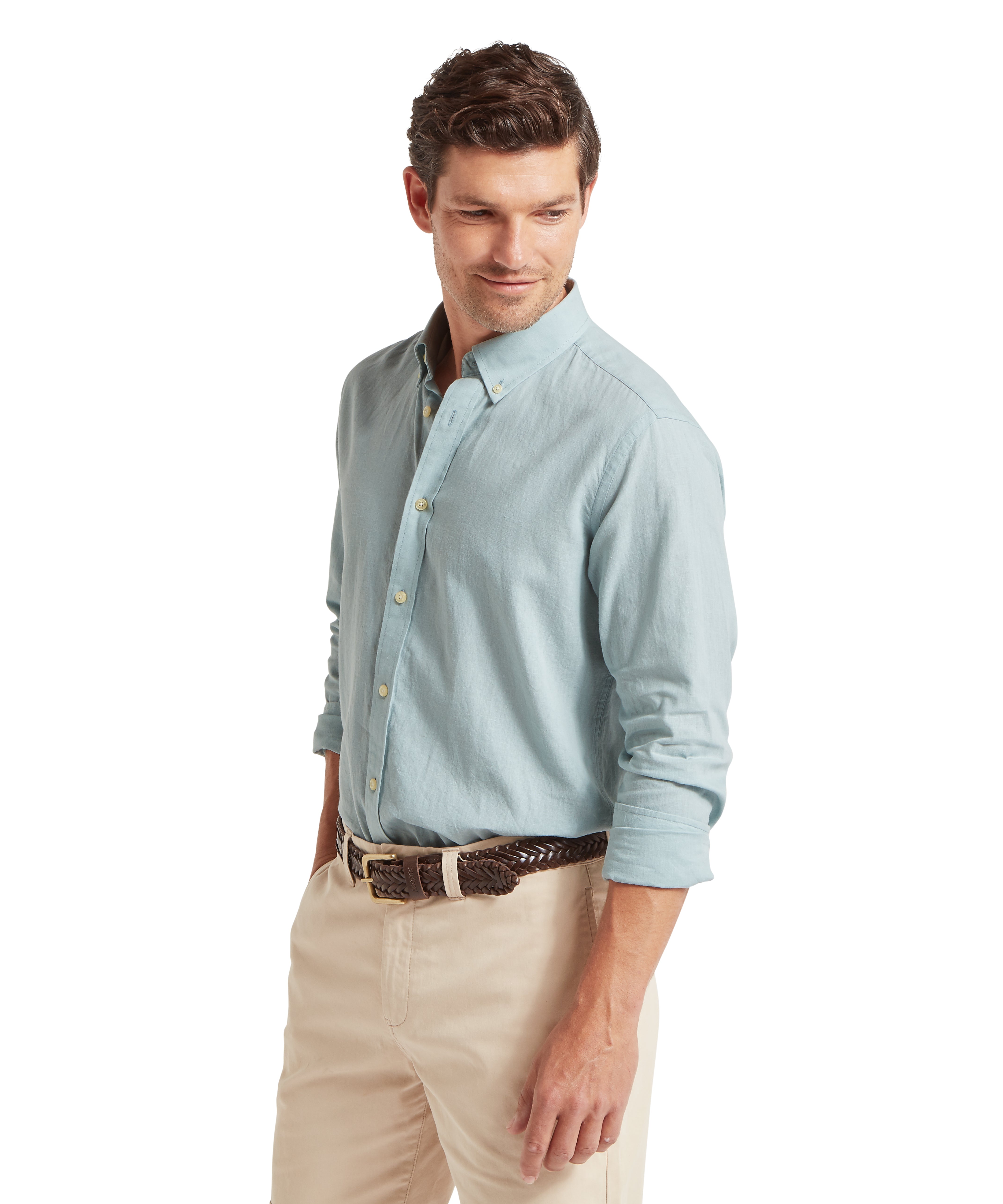 Man wearing a light blue button-up shirt and beige trousers against  white background