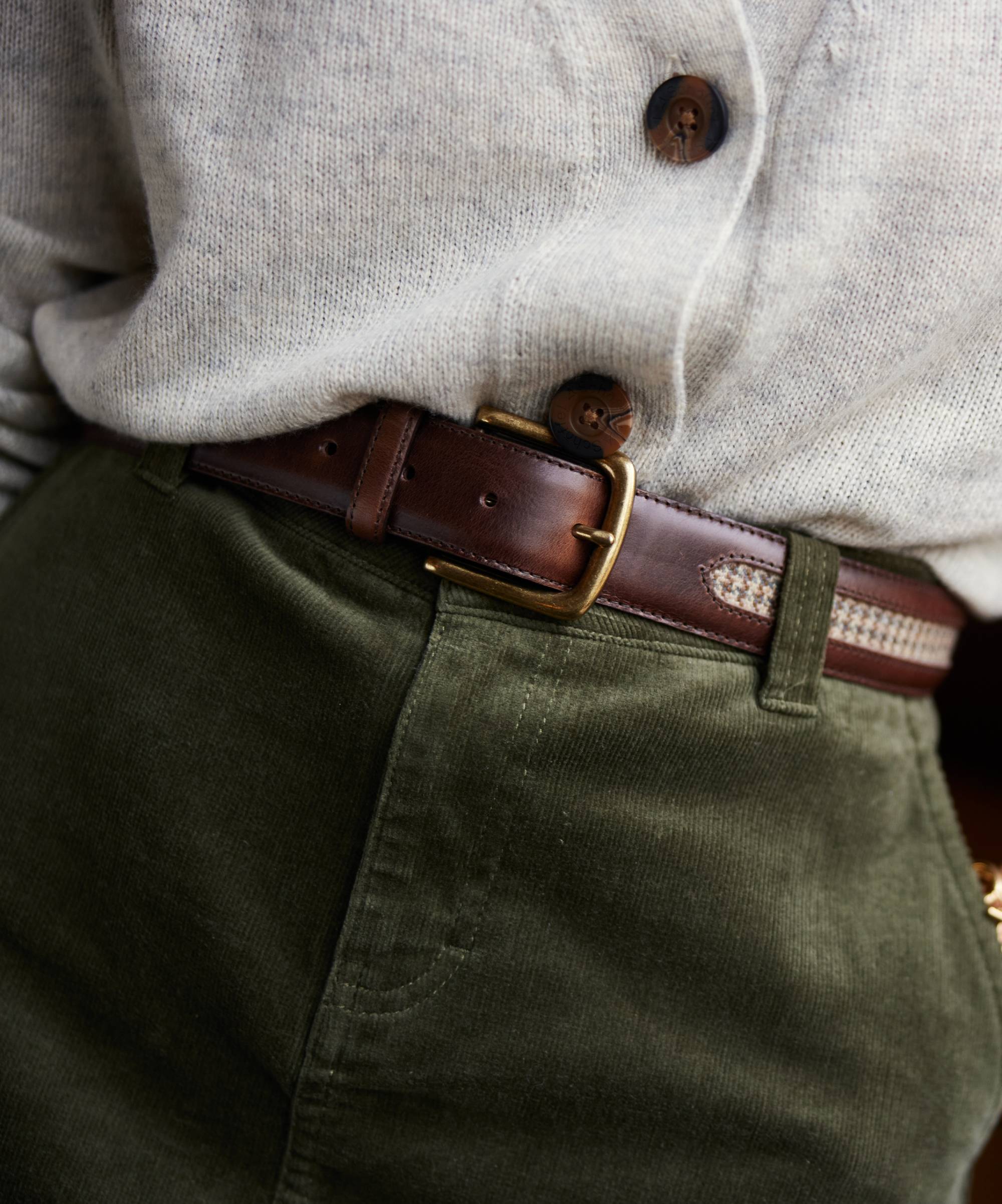 Close-up of a person wearing a brown belt with a gold buckle, olive green pants, and a light grey shirt.