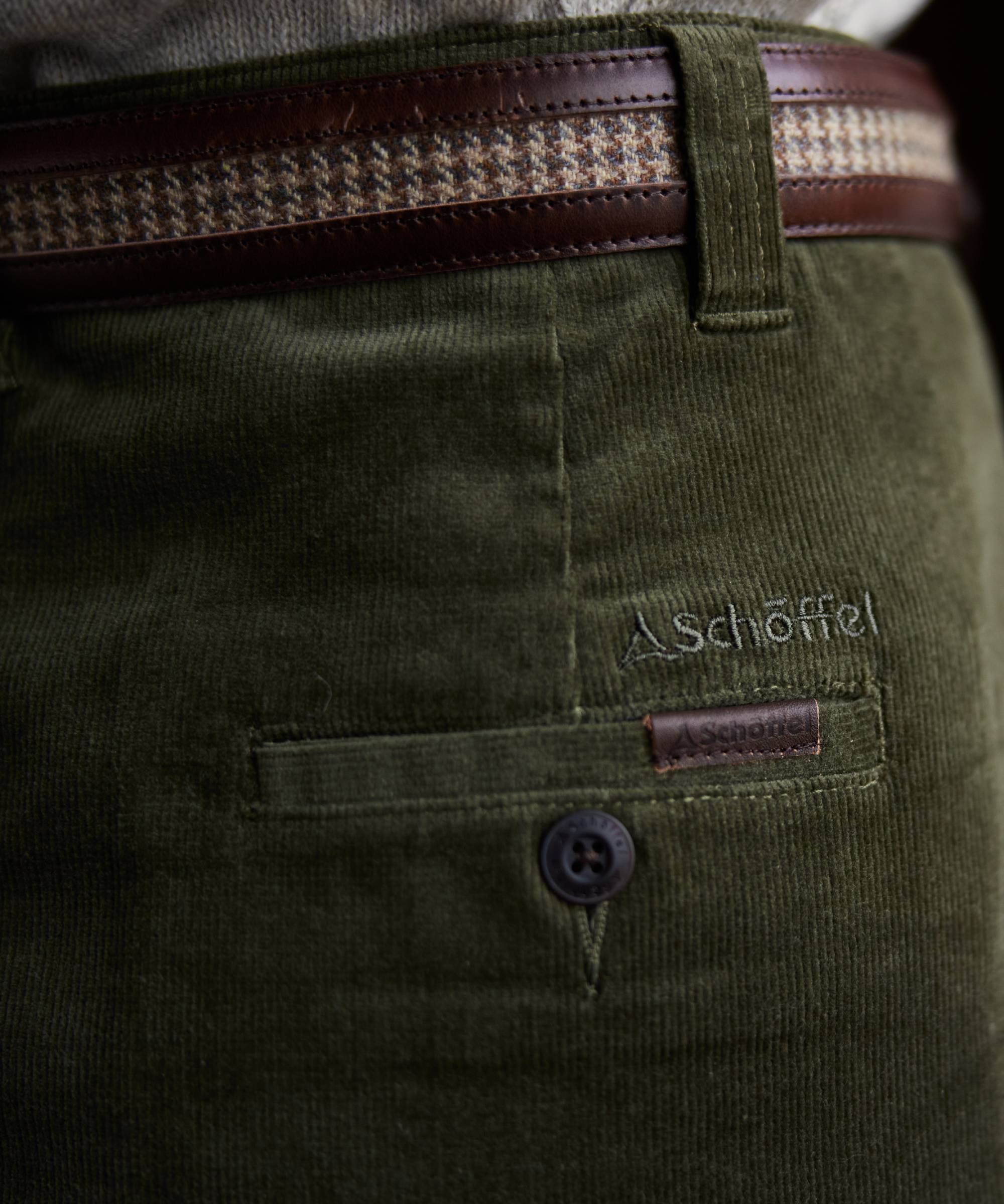 Close-up of green corduroy pants with a Schöffel logo and button detail.