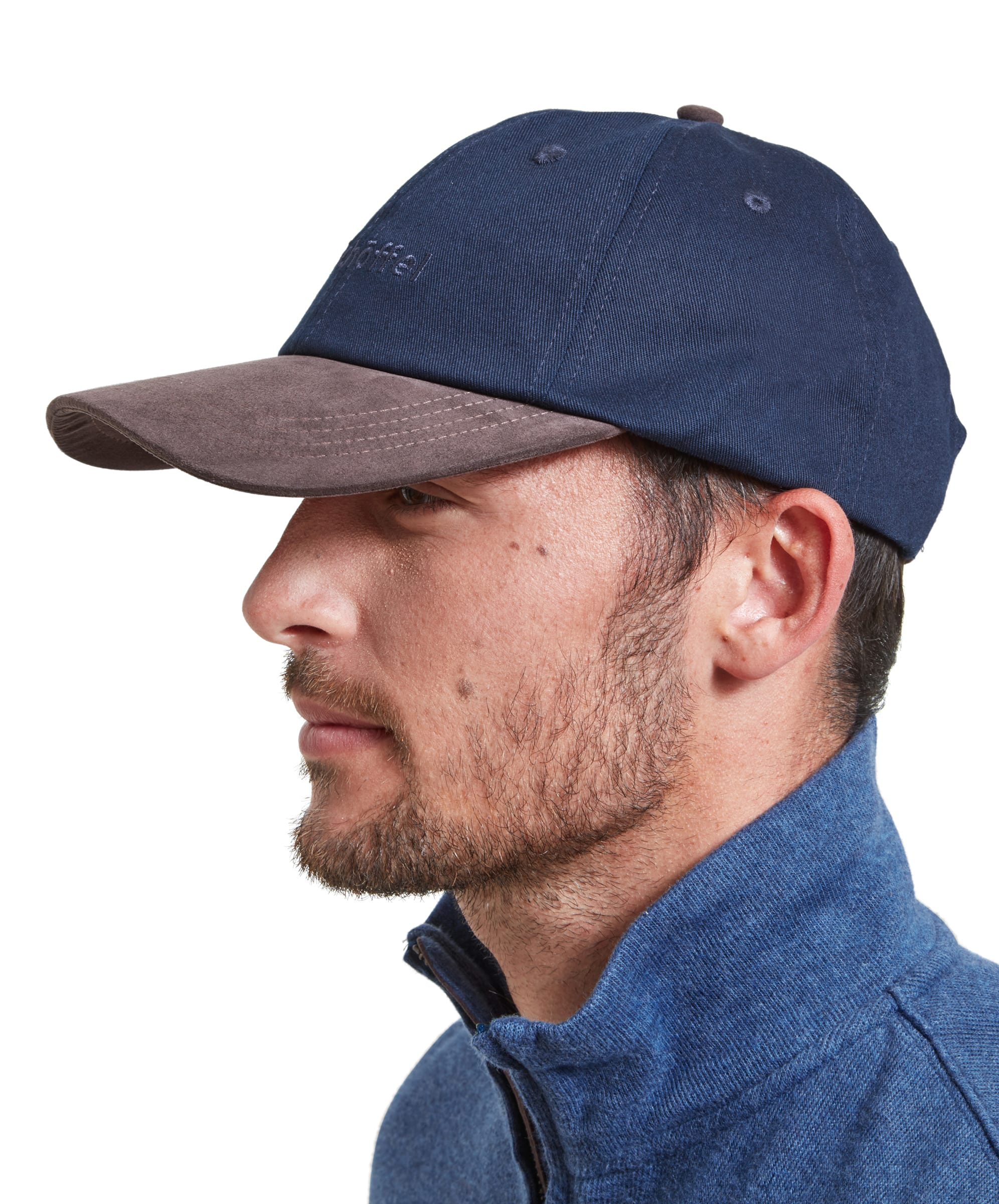 A man with a short beard and wearing a Schöffel Unisex Thurlestone Cap in Navy is shown in profile, wearing a navy blue Schöffel baseball cap with a brown suede brim.