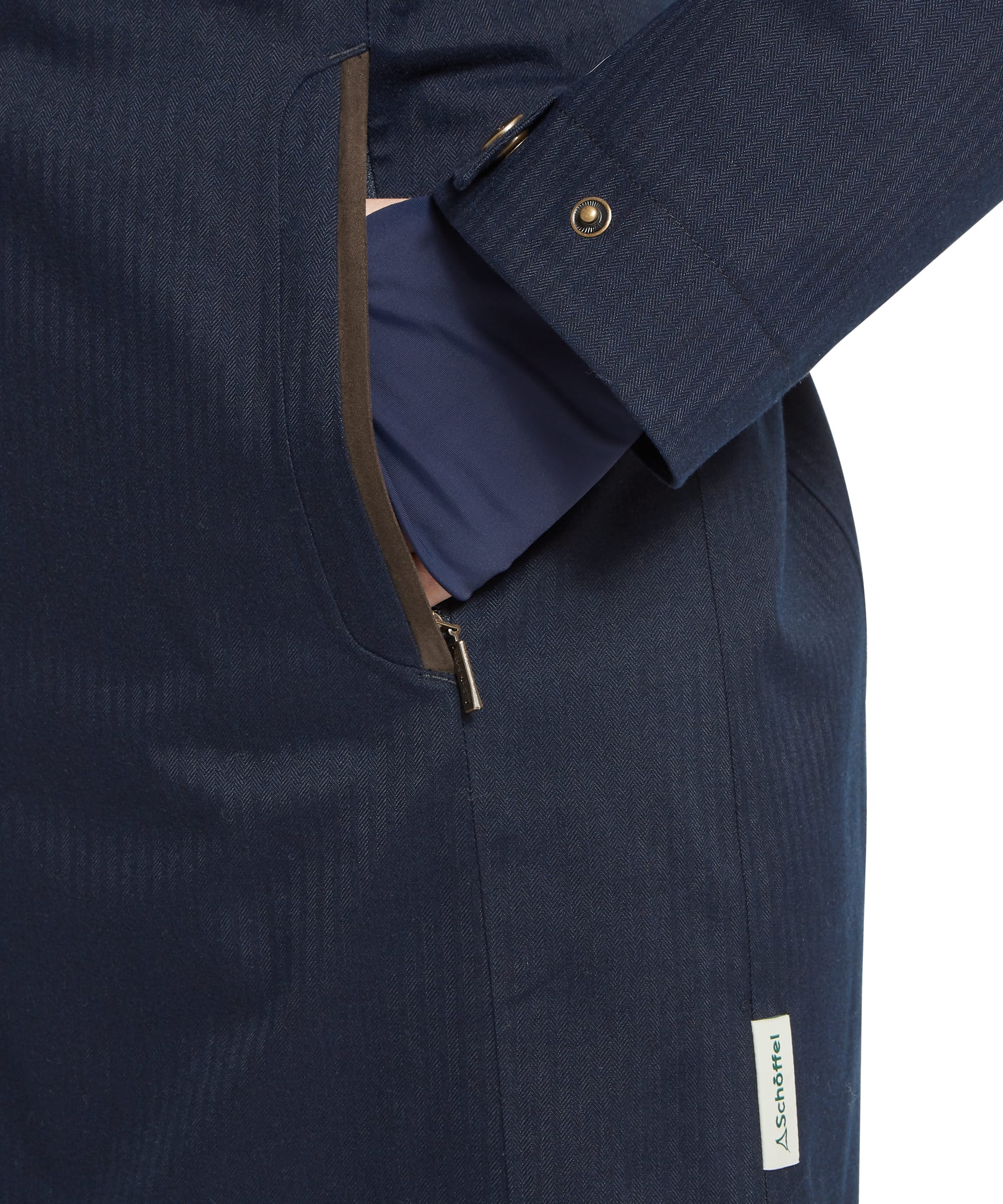 Close-up of the hand-warmer pocket and Schöffel branded snap-fastened cuff on the Women's Allexton Waterproof Coat in Navy, showcasing the herringbone fabric weave and bronze zip detailing