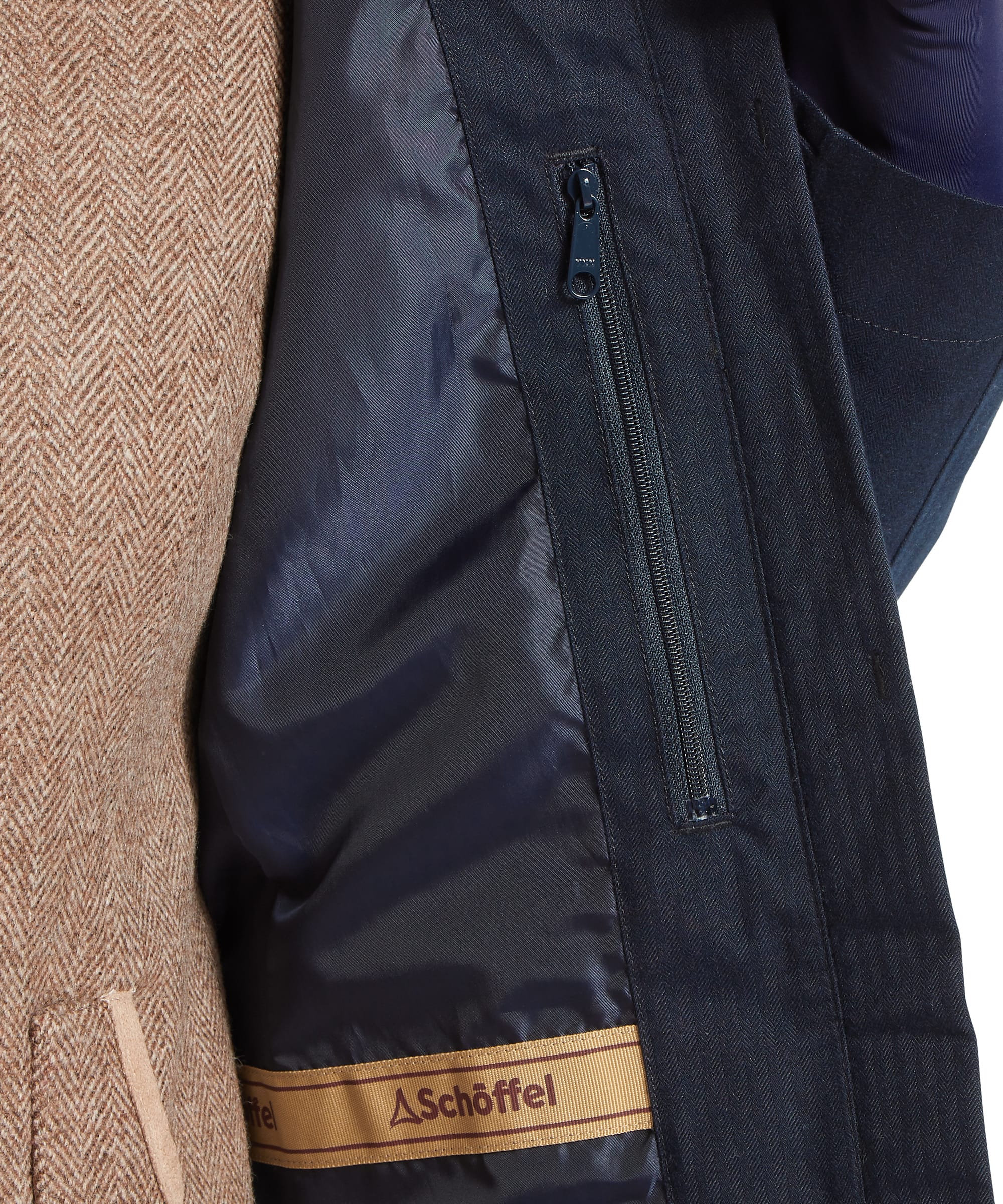 Interior detail of the Schöffel Women's Allexton Waterproof Coat showing the navy lining with inner zip security pocket and branded Schöffel woven label, with caramel tweed lining visible on the left