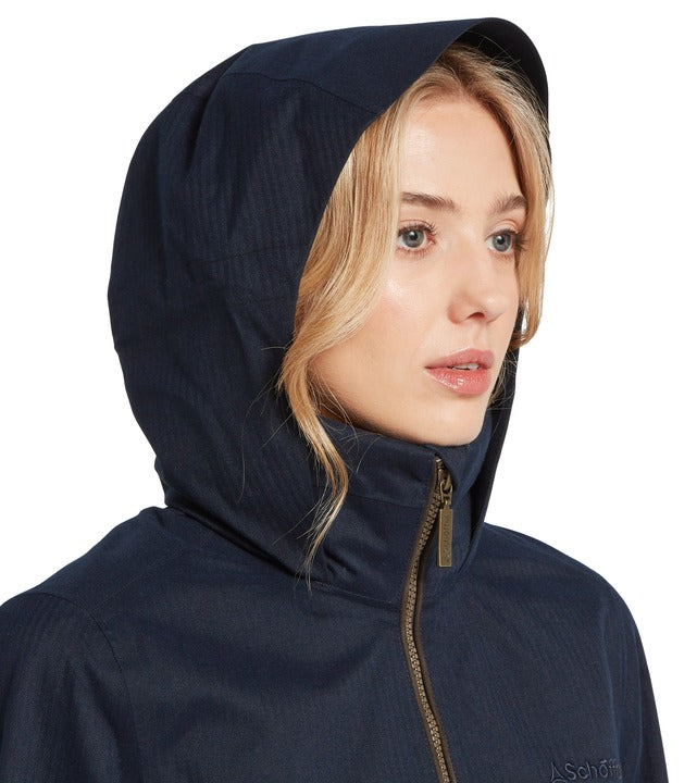 Schöffel Allexton waterproof coat in navy, close-up of woman wearing hood up with full-length zip and embroidered logo
