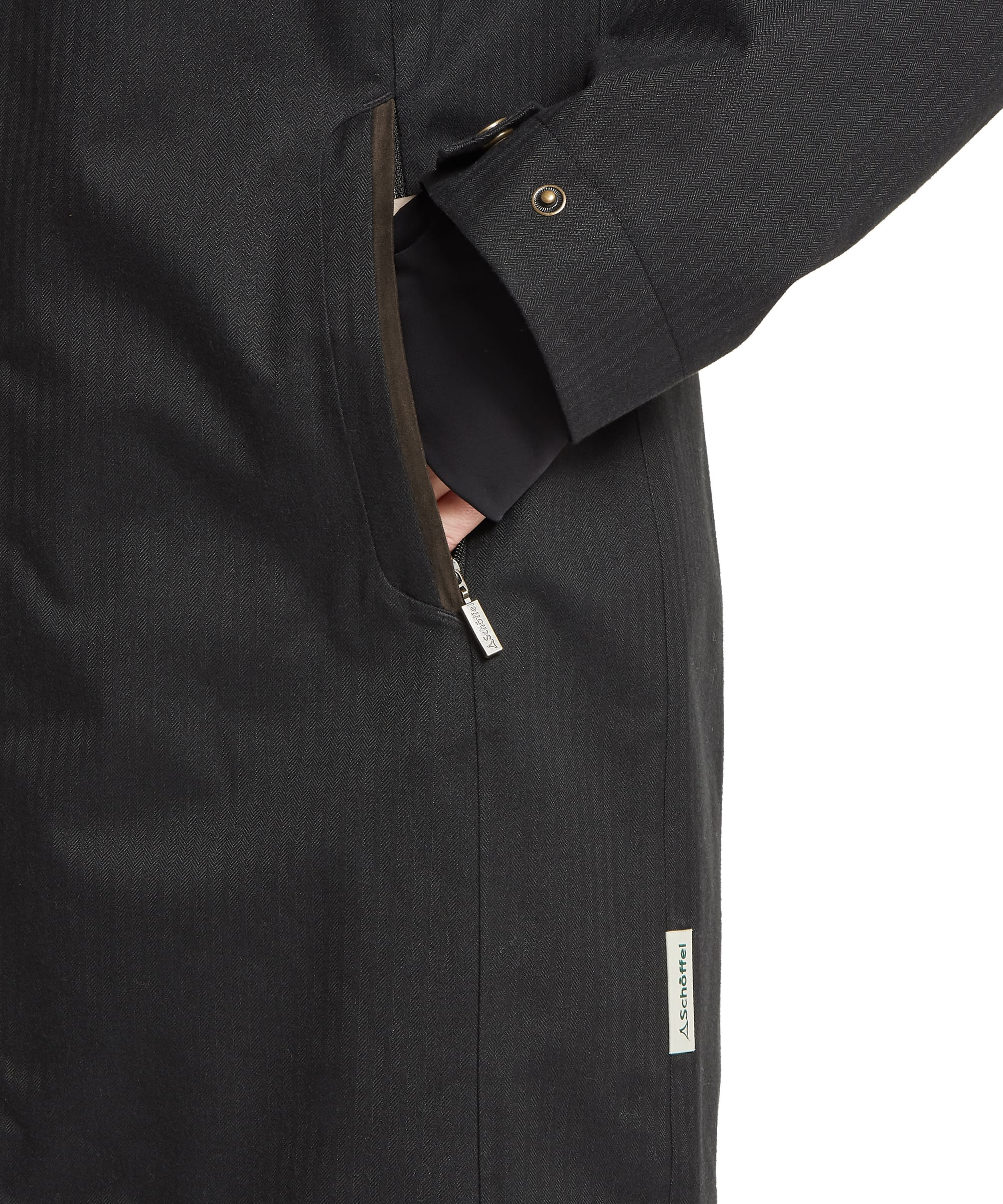 Close-up of the hand-warmer pocket, Schöffel woven label and zip detail on the Women's Allexton Waterproof Coat in Charcoal Herringbone, showing the herringbone fabric weave, zip pocket entry and bronze snap-fastened cuff