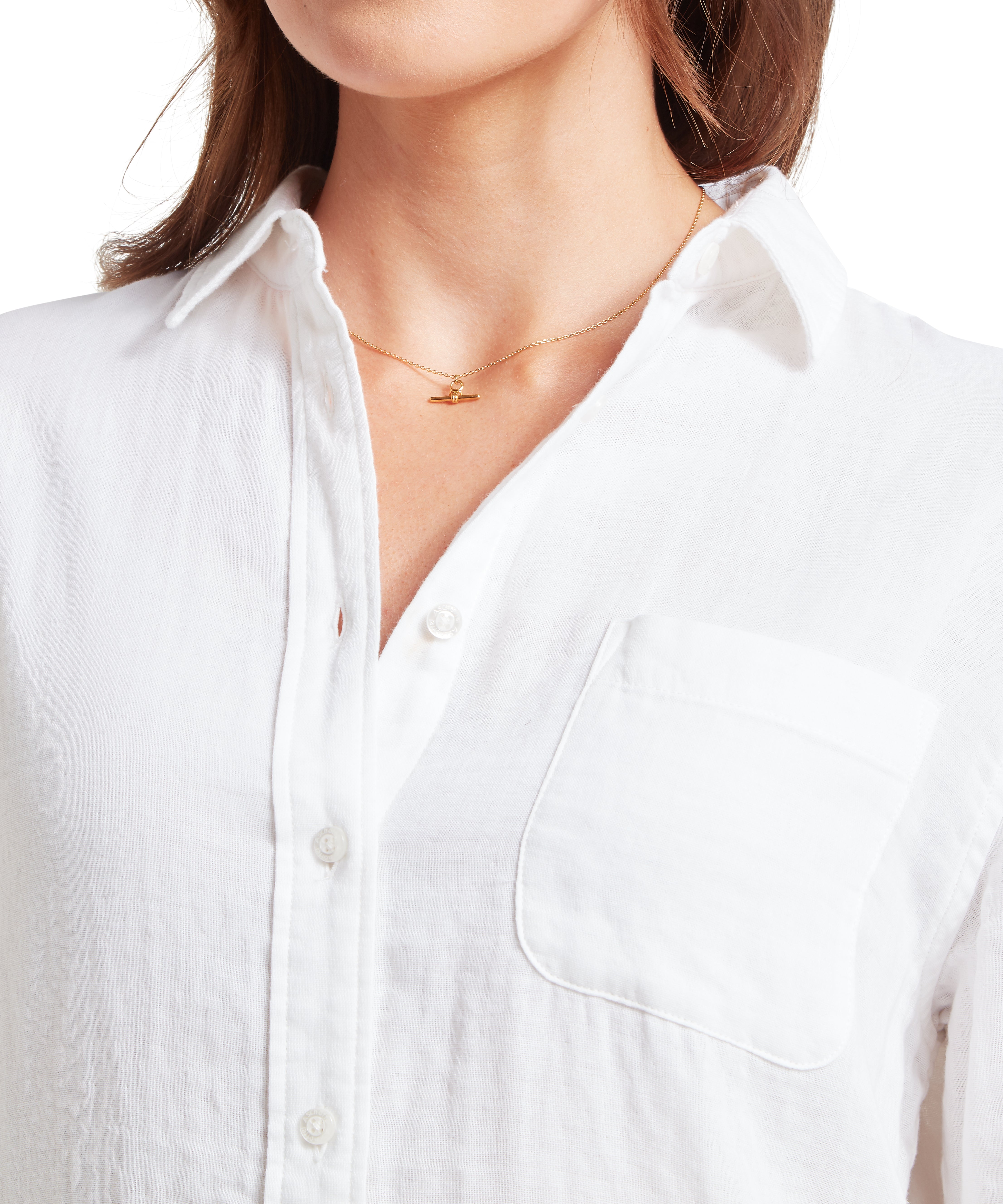 Close-up of a person wearing a white shirt with a necklace.