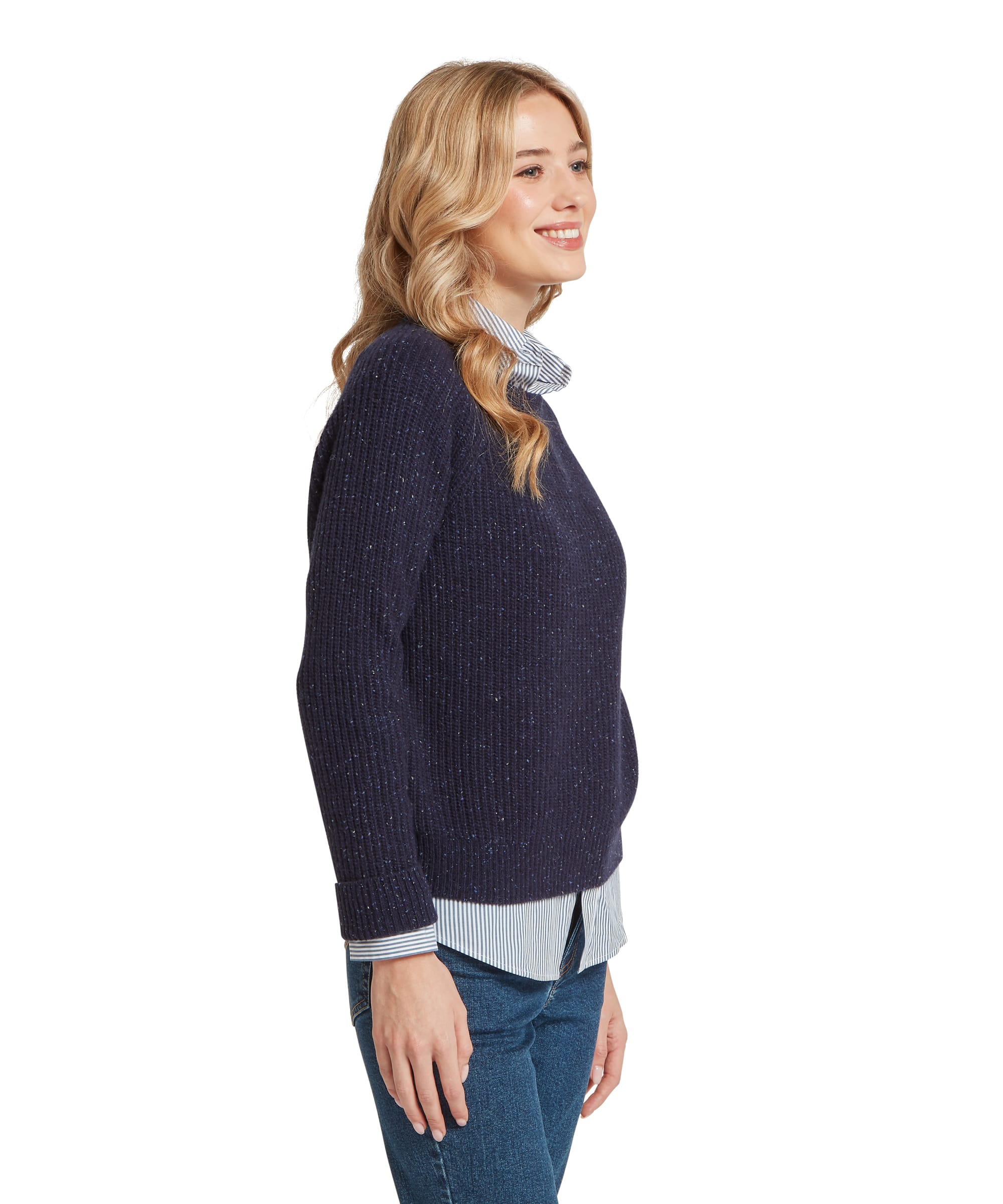 Side view of the Women's Schöffel Balmaha Jumper in navy donegal knit, featuring a relaxed crew neck and ribbed cuffs with flecked yarn texture, layered over a blue and white stripe shirt with blue denim jeans.