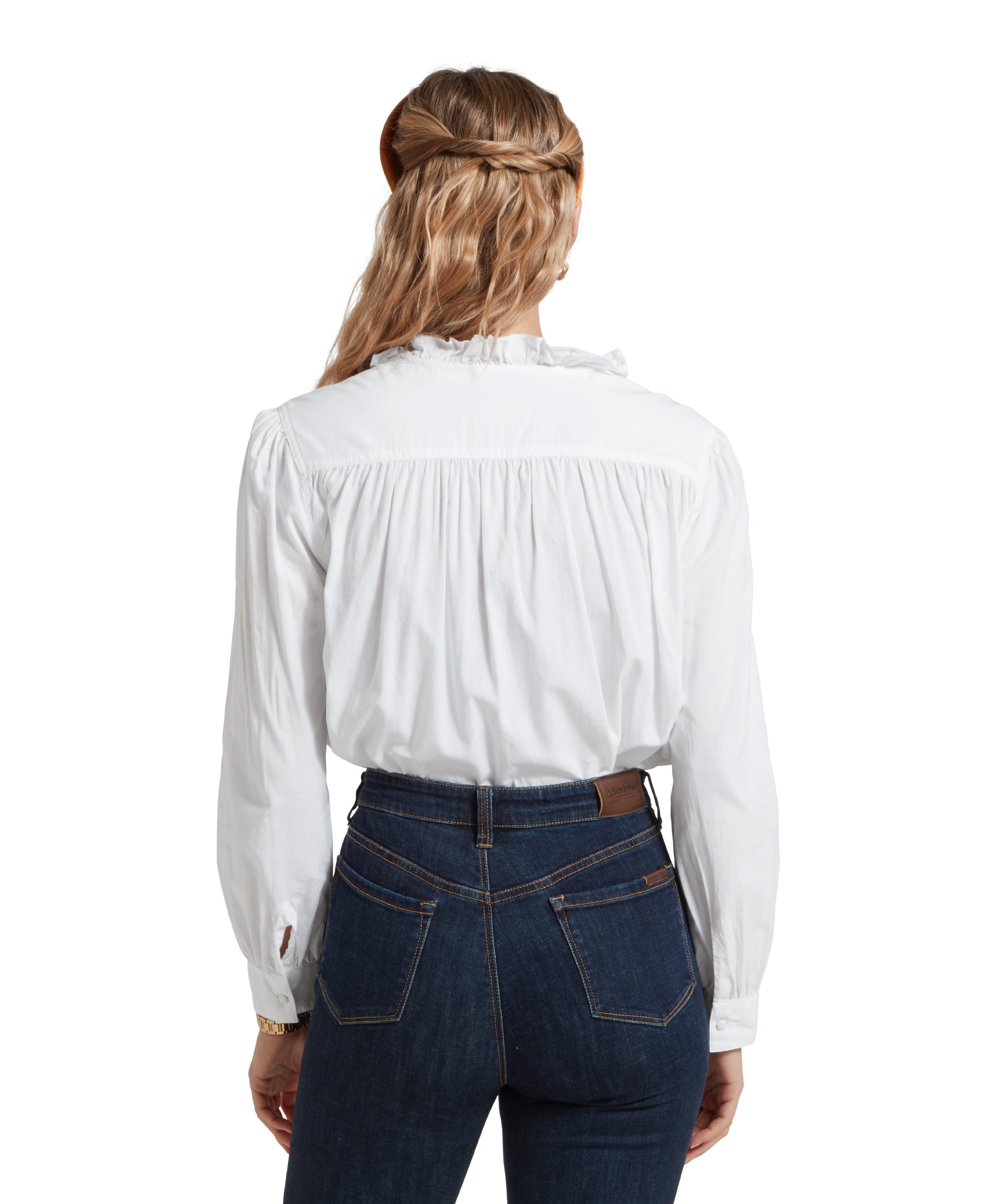 Back image of a female model wearing a tucked in white Schöffel shirt, paired with dark denim jeans and gold accessories.