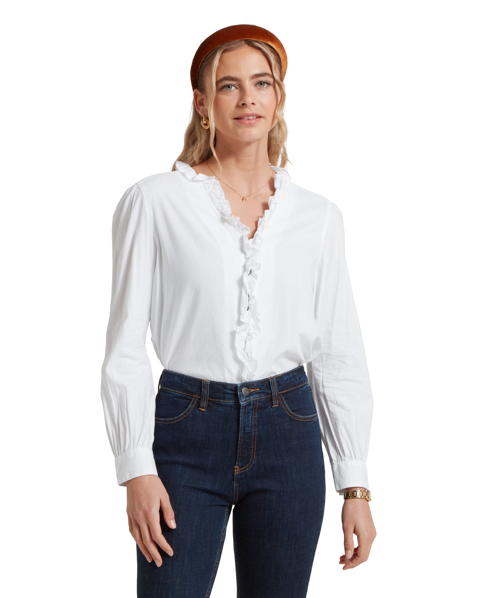 Close up image of a female model wearing a tucked in white Schöffel shirt, paired with dark denim jeans and gold accessories.