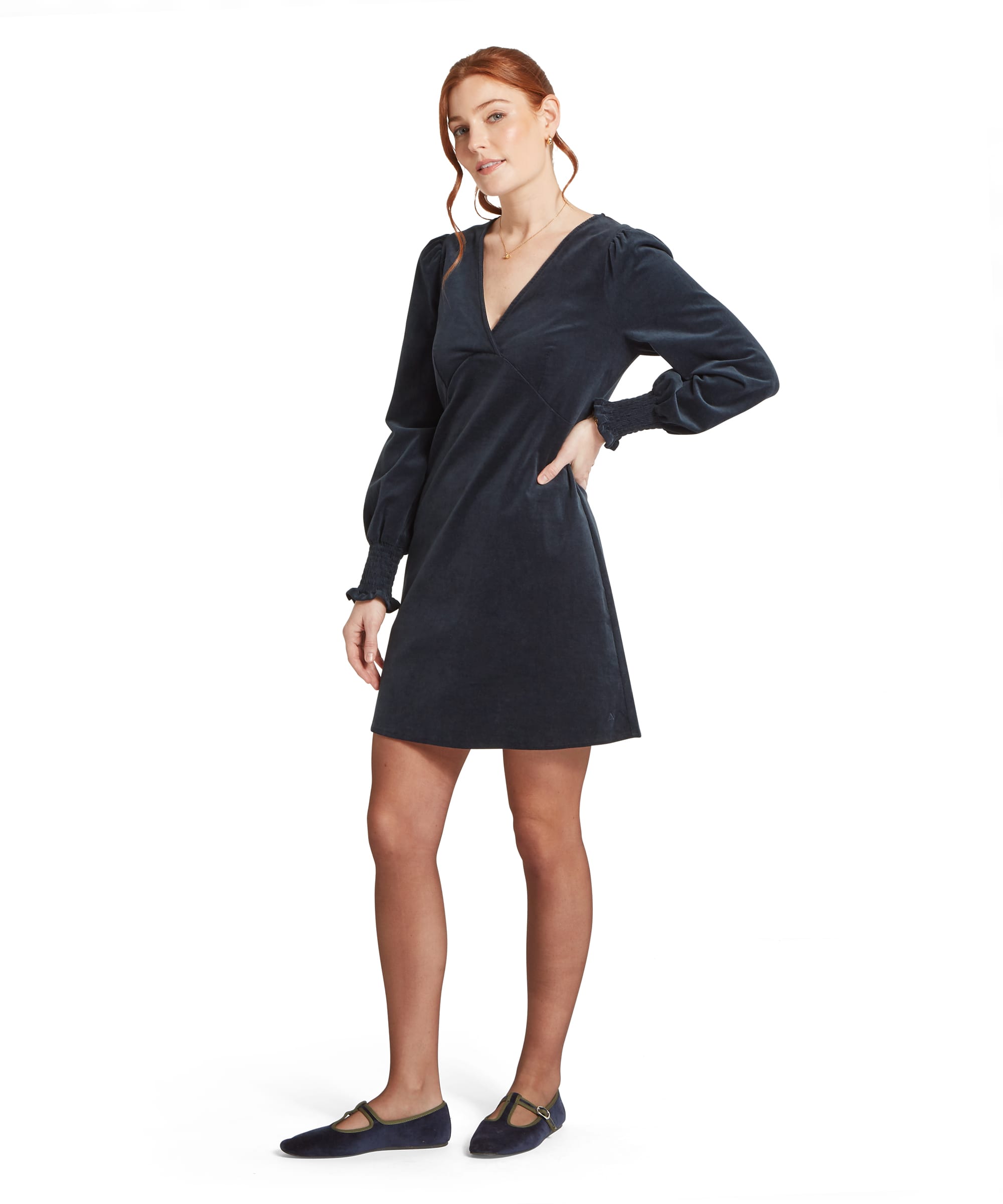Three-quarter view of the Women's Schöffel Briar Cord Dress in navy needlecord, highlighting the elegant V-neckline, empire-line seaming and fluid A-line skirt, styled with navy velvet T-bar flats and a delicate gold necklace.