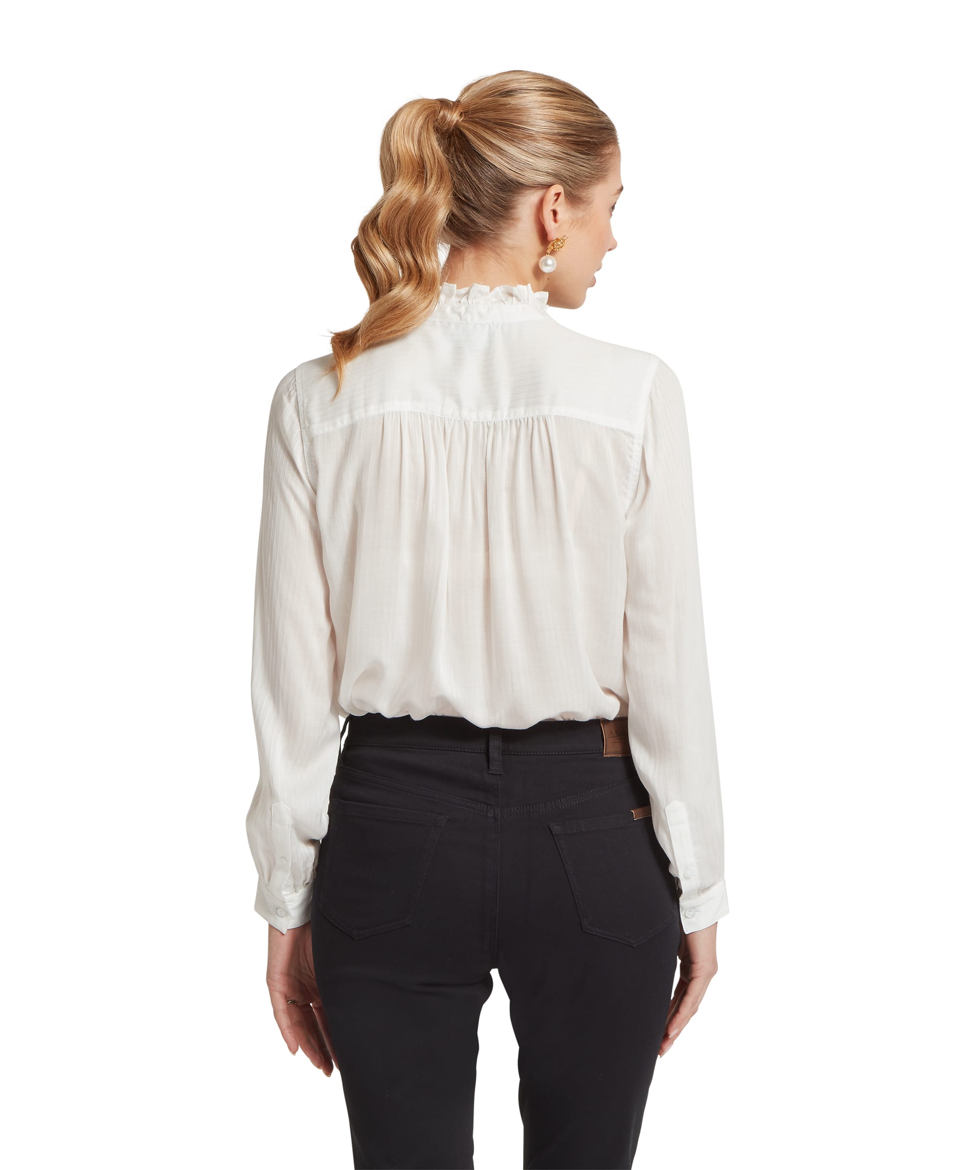 Rear view of the Women's Schöffel Chelsworth Blouse in white, showing the gathered yoke back detail with fine self-stripe fabric and frilled standing collar, tucked into slim black trousers with a Schöffel leather-tab waistband.