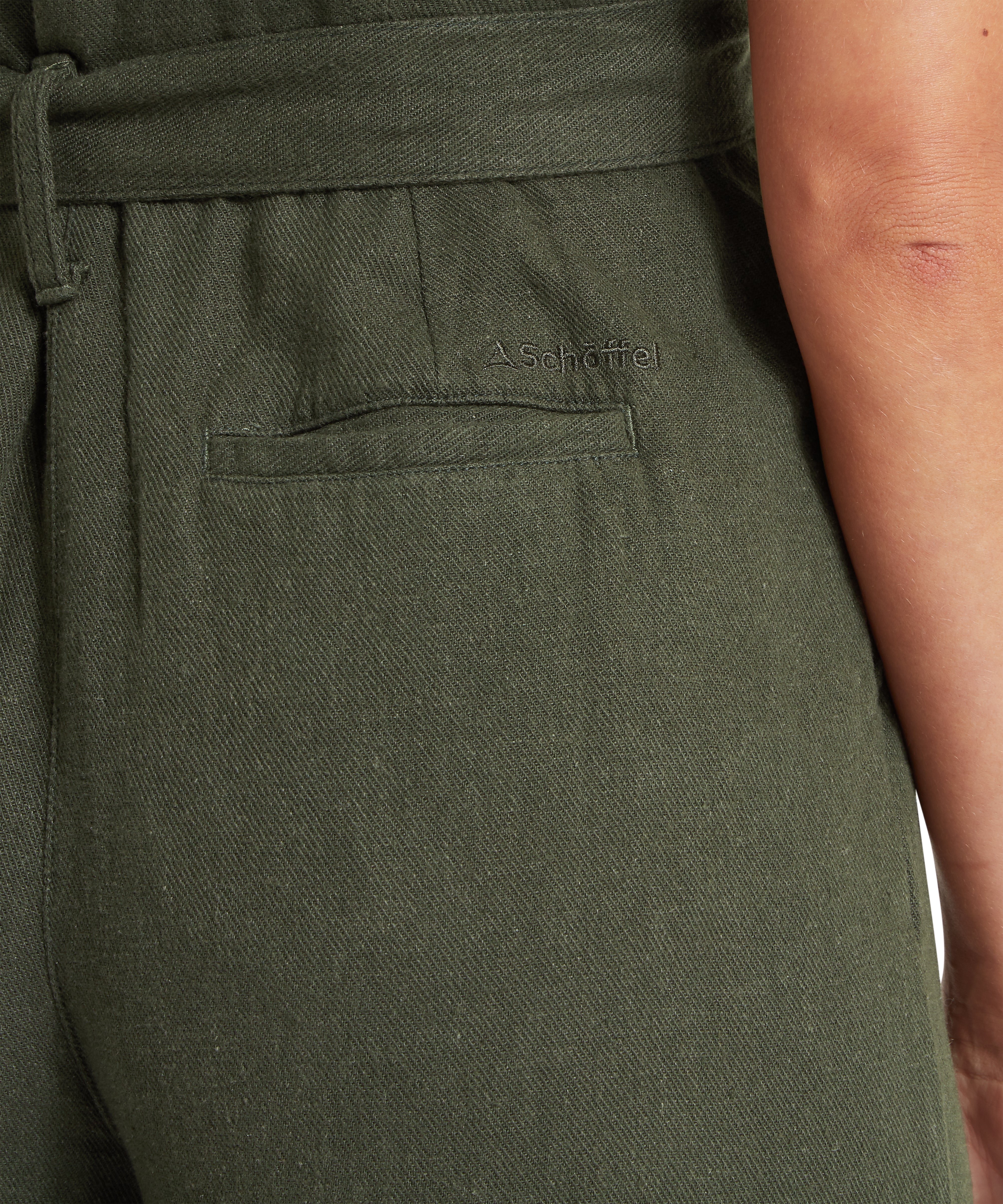 Close up of a green jumpsuit featuring a Schöffel logo above a pocket.