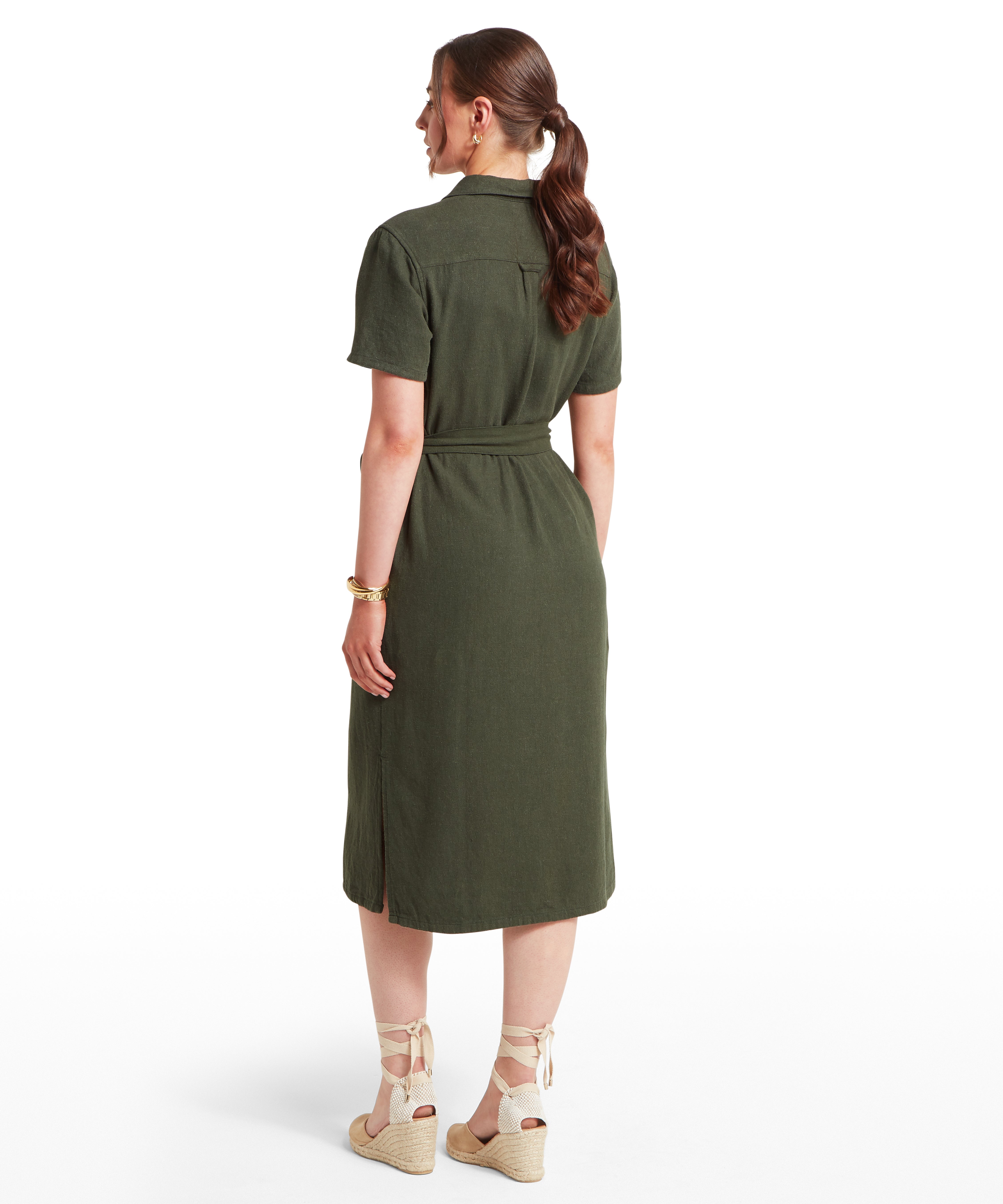 Woman facing backwards wearing a green dress on a white background