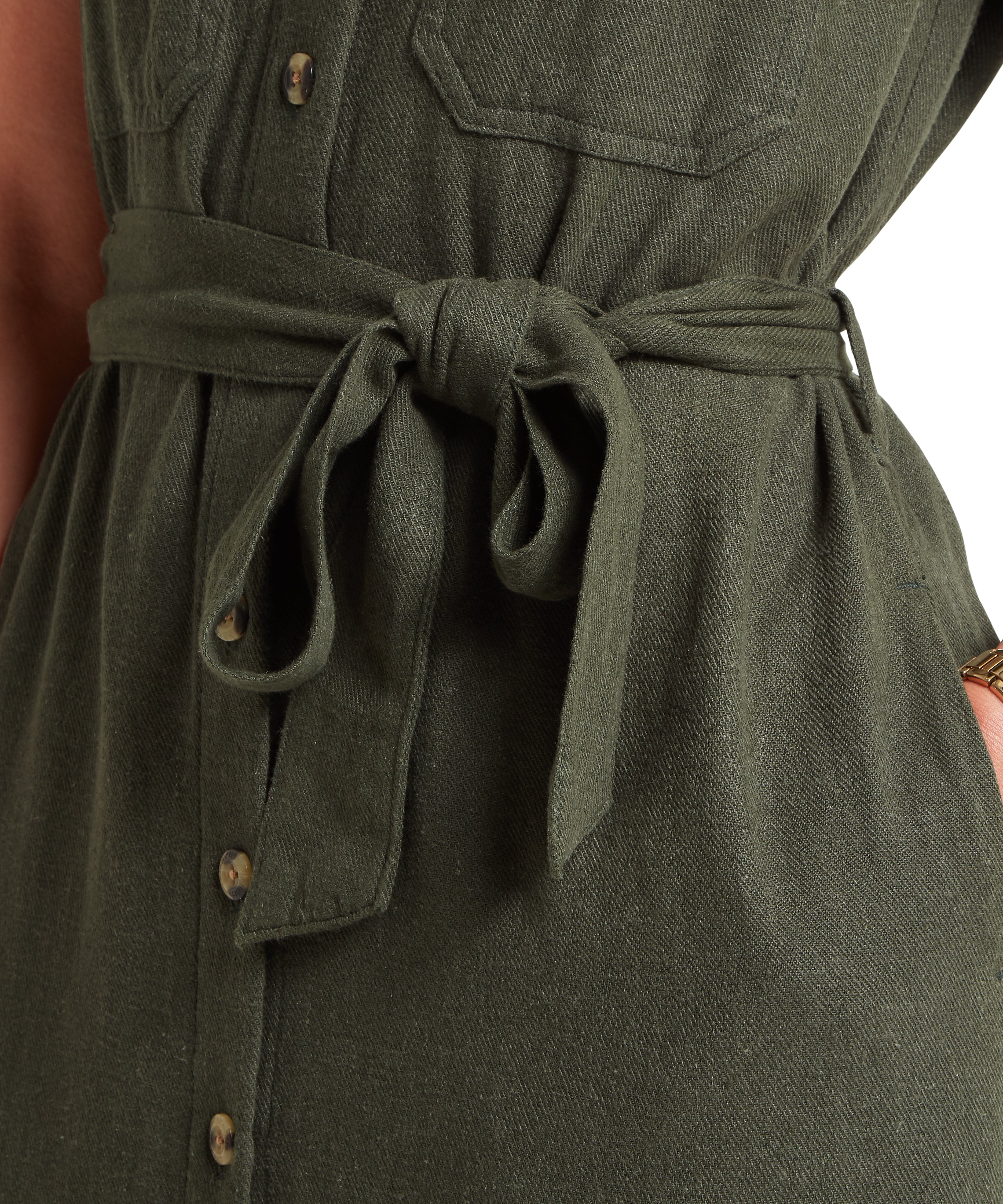 Close up of a green linen dress, highlighting the tie belt, which is tied in a bow.