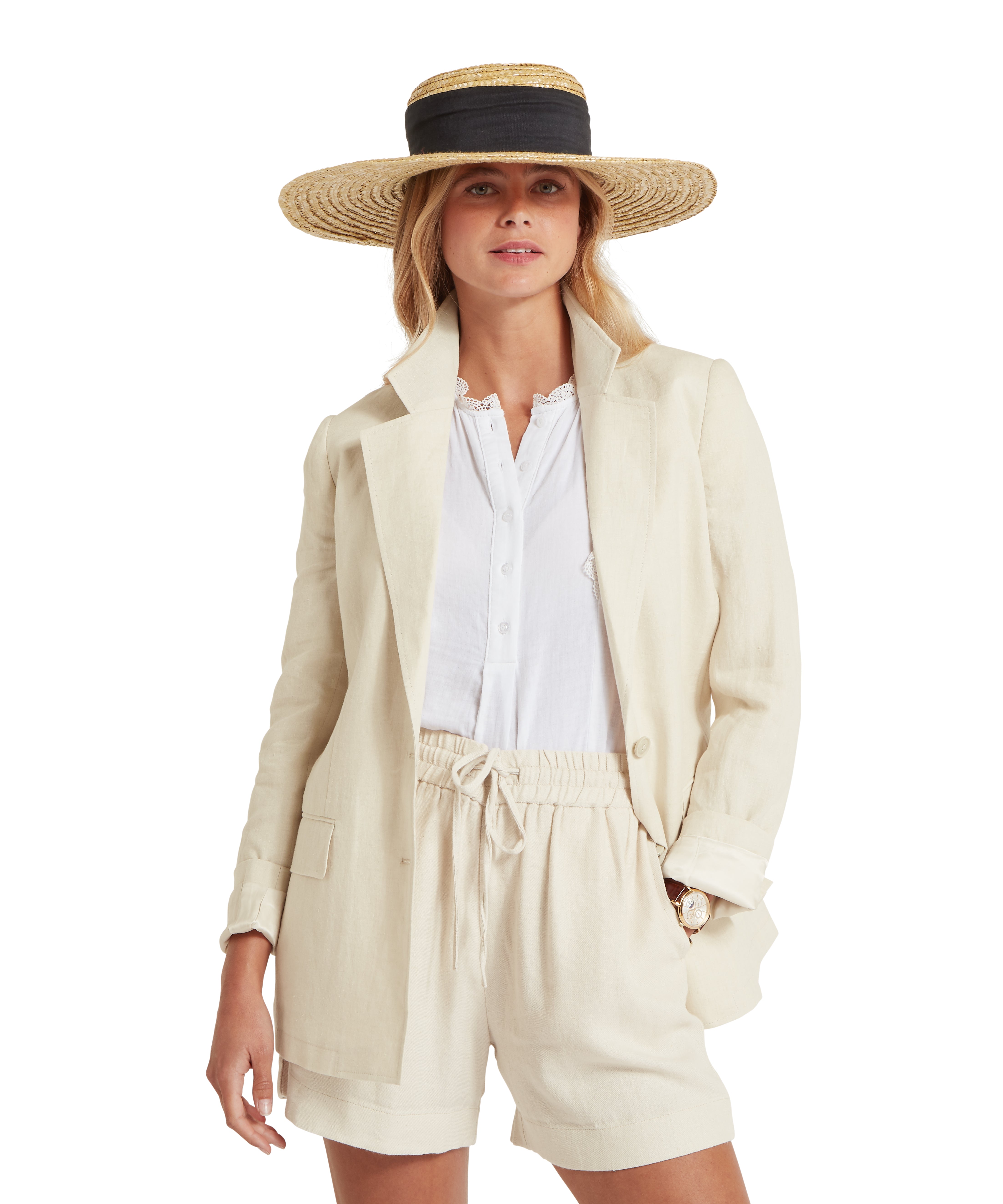 Woman wearing a coordinated outfit consisting of a light cream blazer, white button-up blouse, and matching cream drawstring shorts. She also wears a wide-brimmed straw hat with a black band. Displayed against a plain white background, the outfit blends casual and polished elements for a summery look.