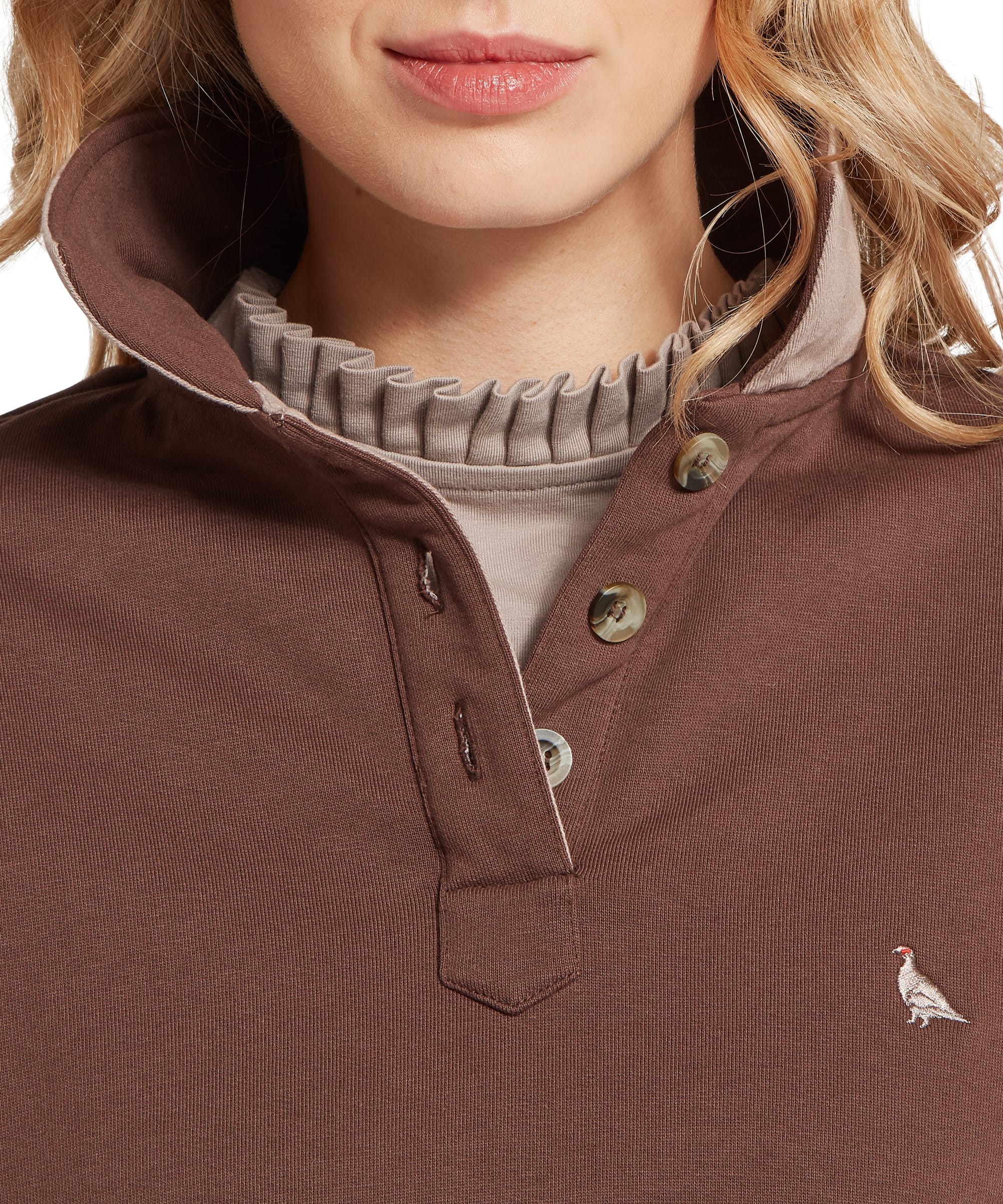Close-up of the snap-button placket, contrast camel storm collar and embroidered Schöffel guinea fowl logo on the Women's Horseley Rugby Sweatshirt in Chocolate Brown, with a cream ribbed polo neck visible underneath