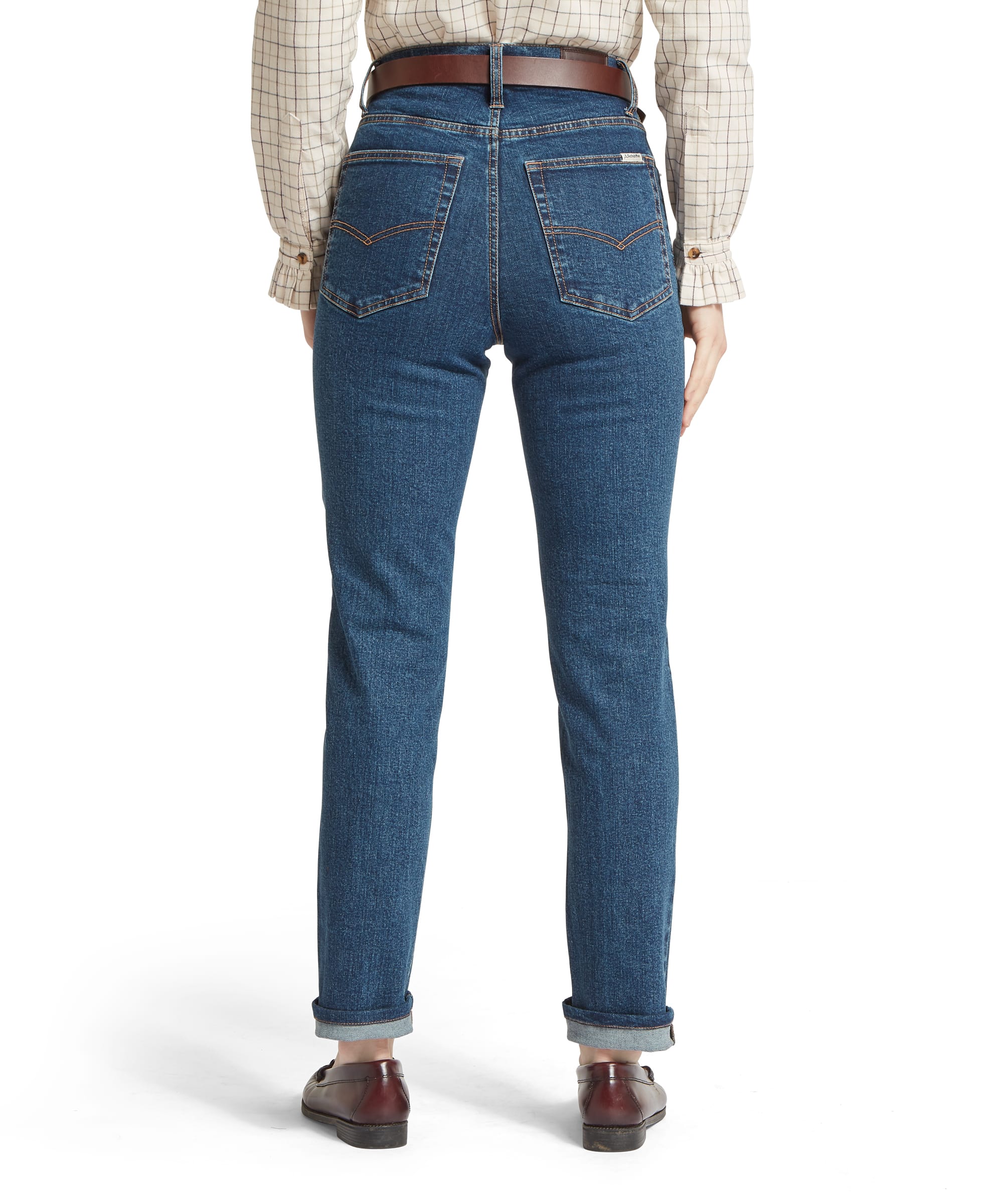 Schöffel Women's Ivy Jean in mid blue denim, rear view showing high-rise waistband, V-bar back pocket stitching, contrast amber topstitching, Schöffel woven label, and turn-up hem, worn with a cream windowpane-check shirt and dark horsebit loafers