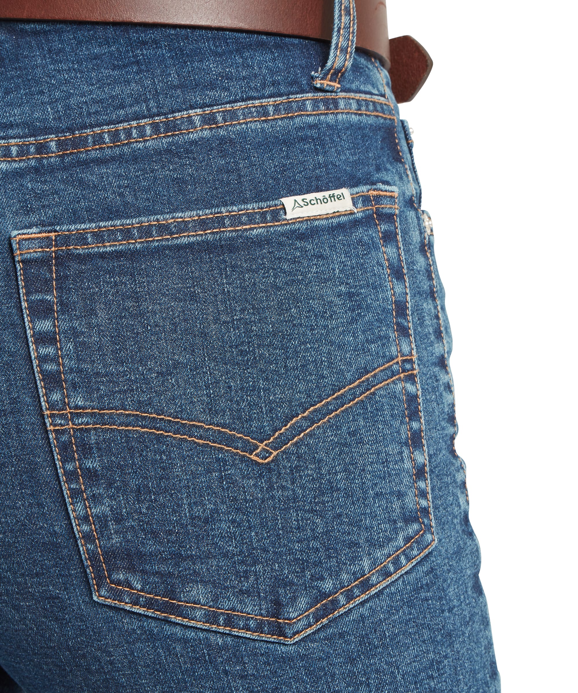 Close-up of the back pocket detail on Schöffel Women's Ivy Jean in mid blue denim, showing contrast amber stitching, V-bar pocket design, and embroidered Schöffel label with brown leather belt visible at waistband