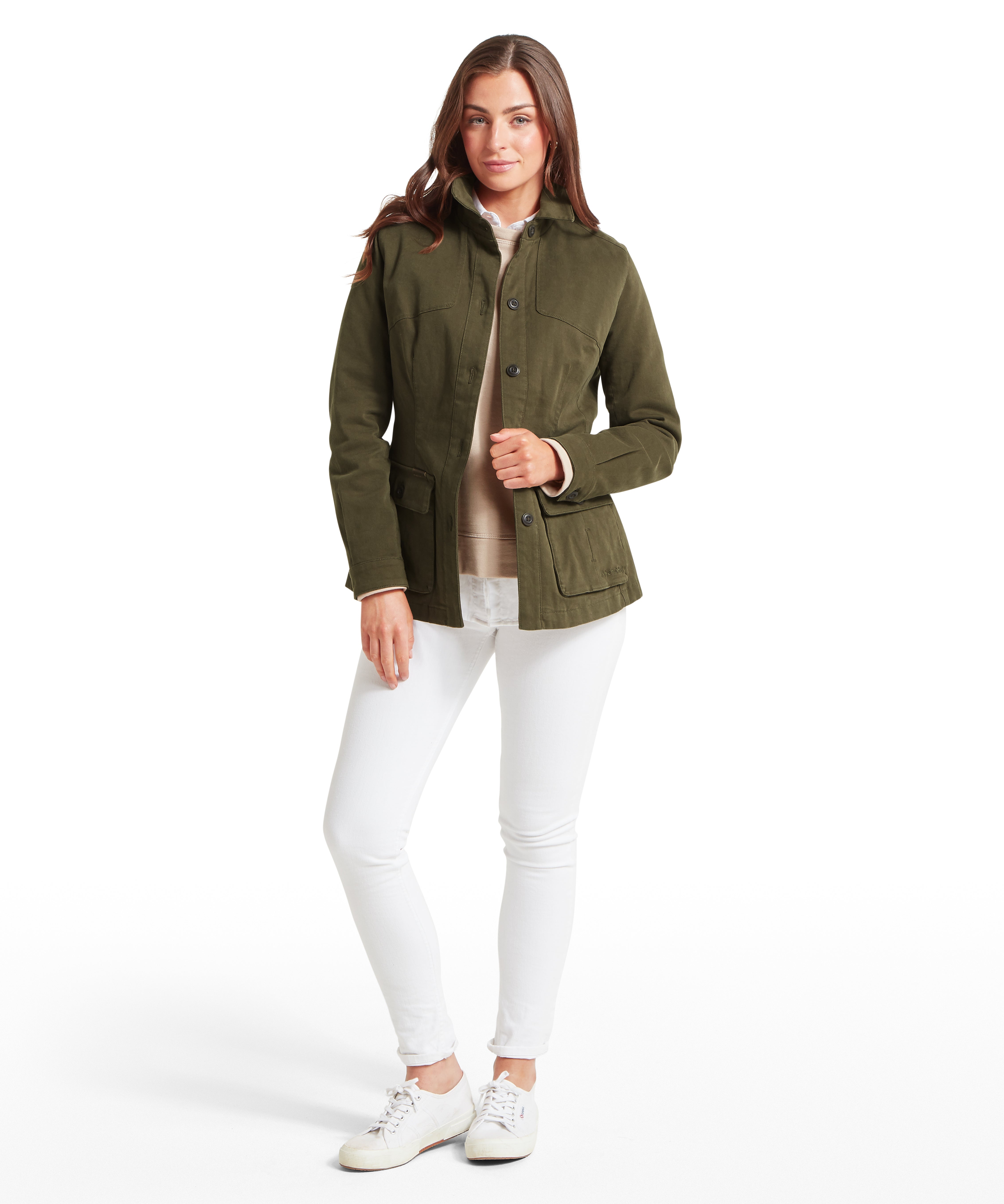 Woman wearing a green jacket and white trousers against a white background