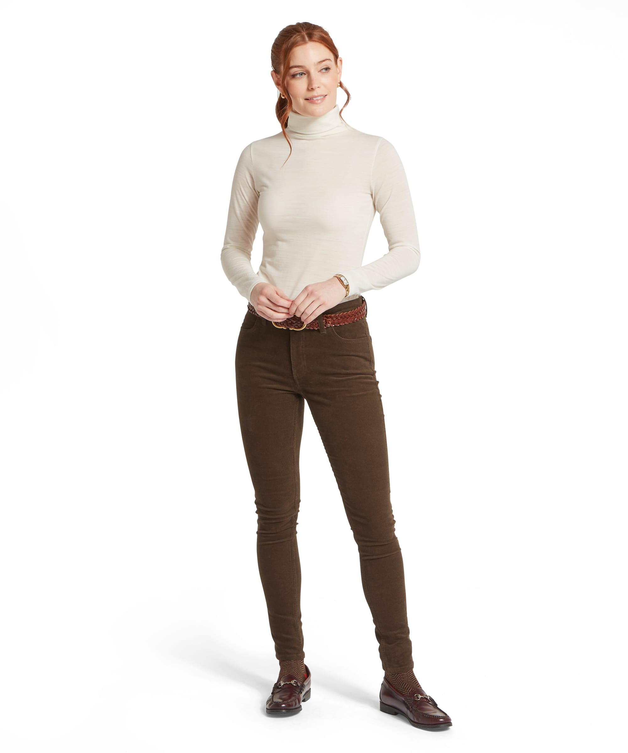 Schöffel Women's Malton Merino Top in ivory white, full-length front view of a slim-fit roll-neck base layer worn with dark brown corduroy trousers, a plaited leather belt, and horsebit loafers