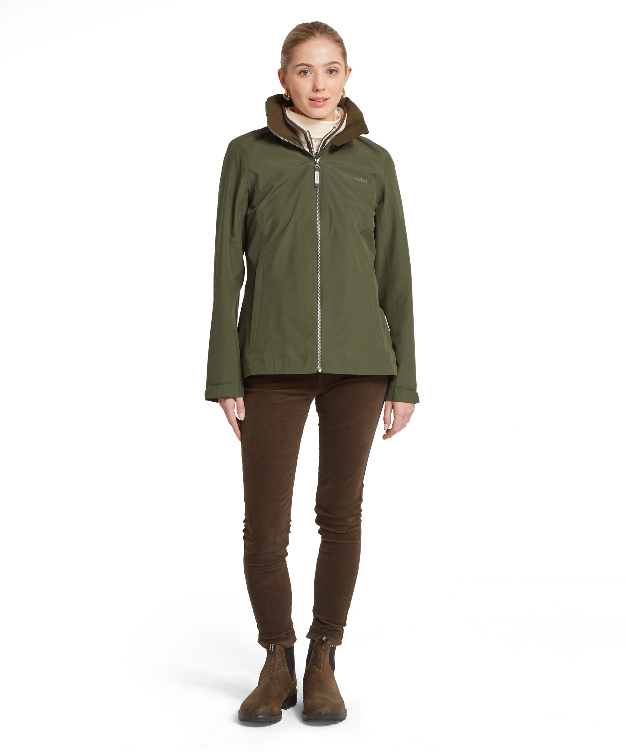 Full-length front view of the Schöffel Women's Manton Lightweight Waterproof Jacket in Dark Olive, showing the clean streamlined silhouette, zip-through fastening and relaxed fit, worn with dark corduroy trousers and suede ankle boots