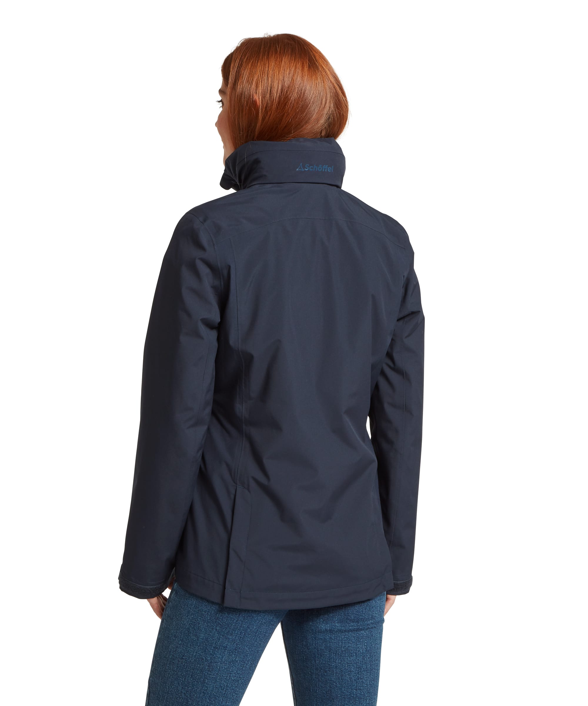 Rear view of the Women's Schöffel Manton Lightweight Waterproof Jacket in midnight navy, showing the tonal Schöffel logo embroidery at the back of the stand collar, clean back seaming and waterproof shell fabric, worn with blue jeans.